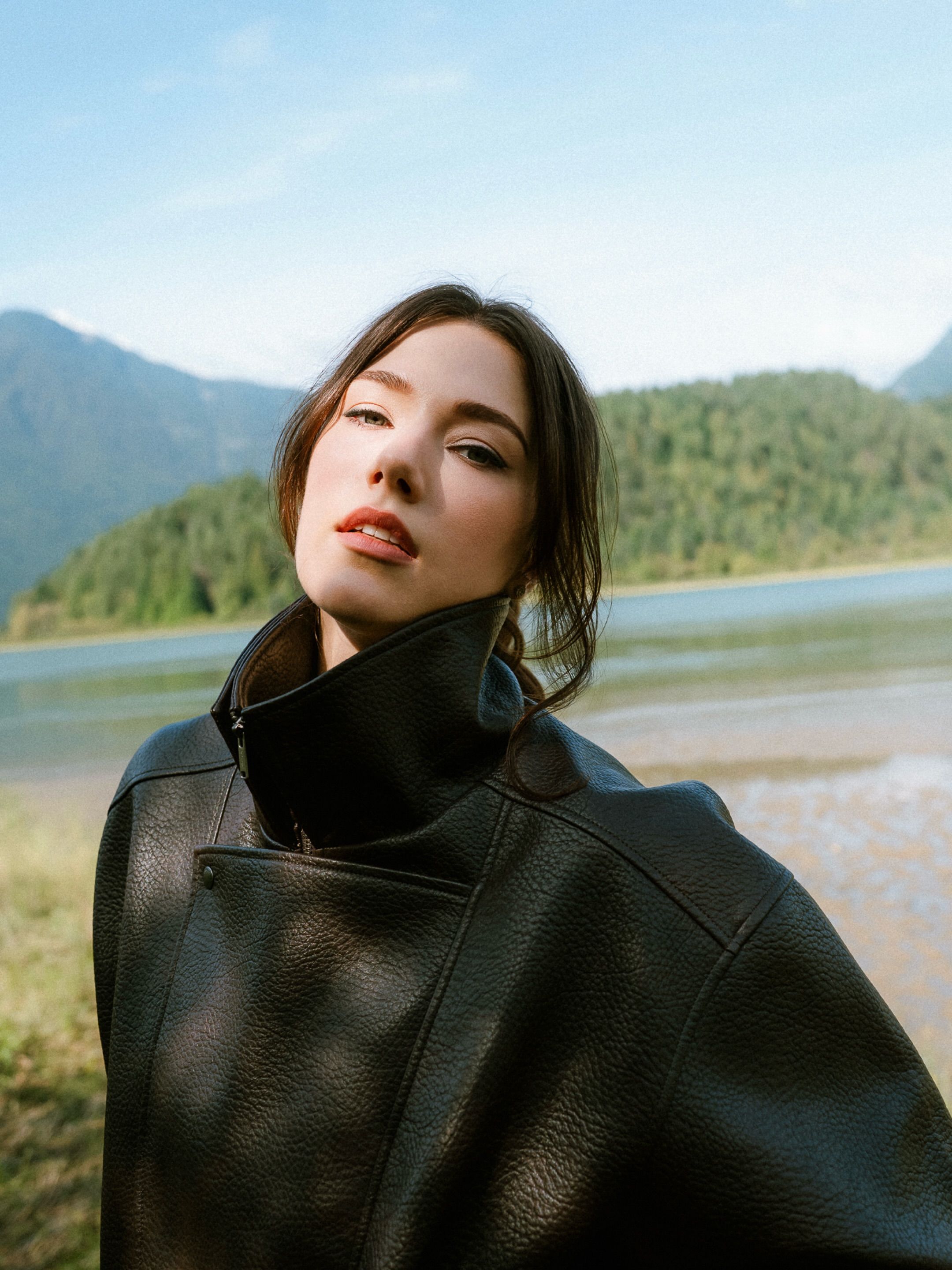 Woman in a black leather jacket beside a mountain lake, portrait session