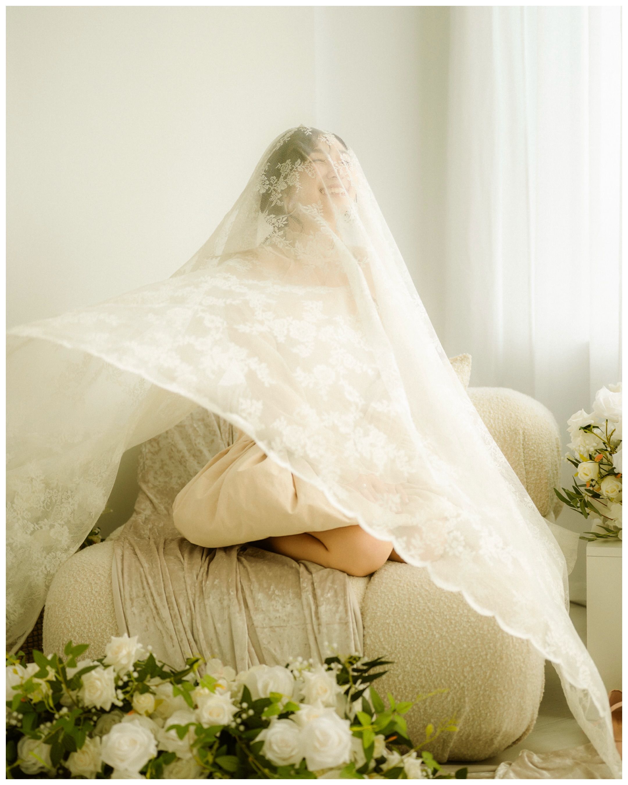 Bride under a lace veil in soft window light