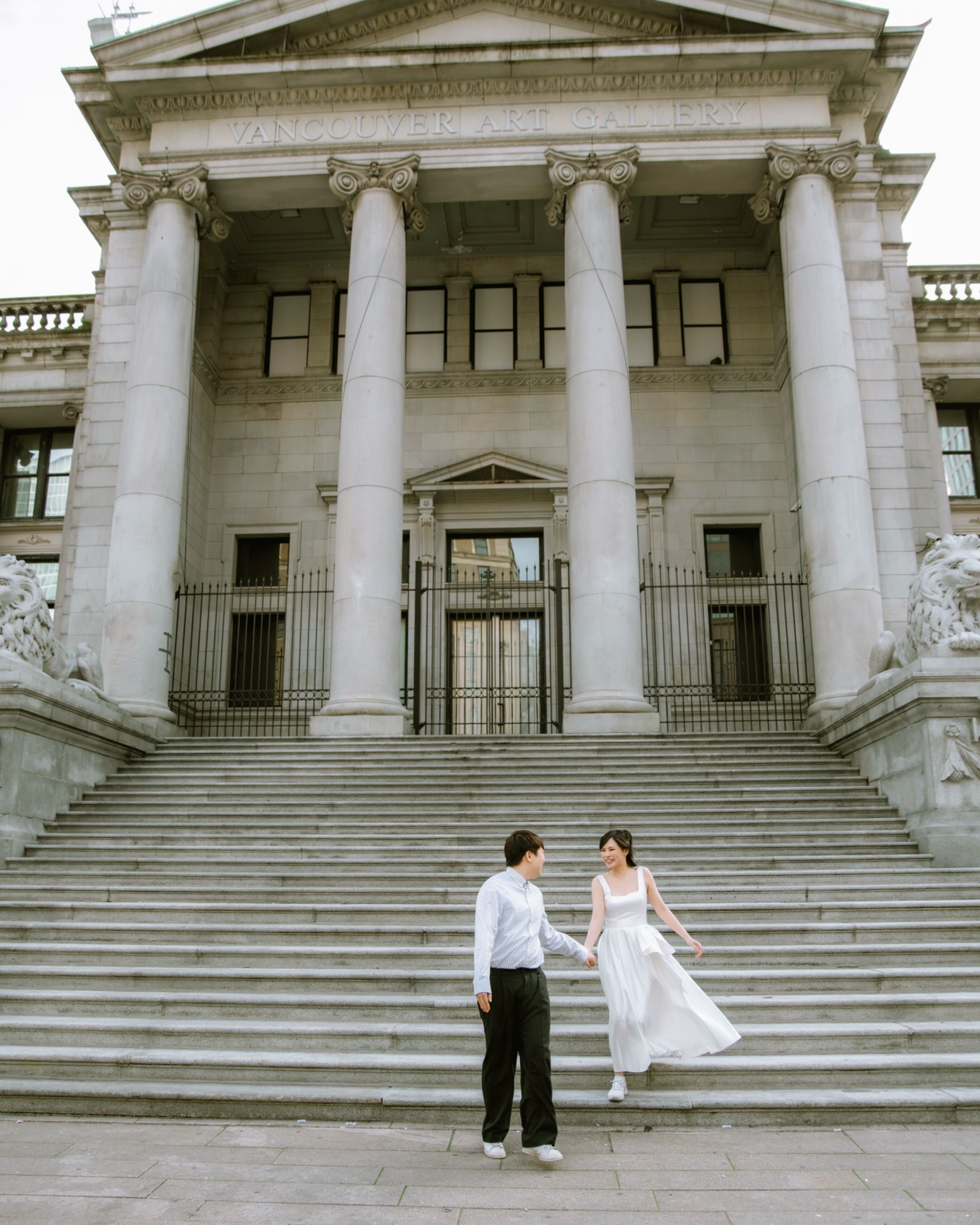 Bride and groom on the stone steps of a columned building