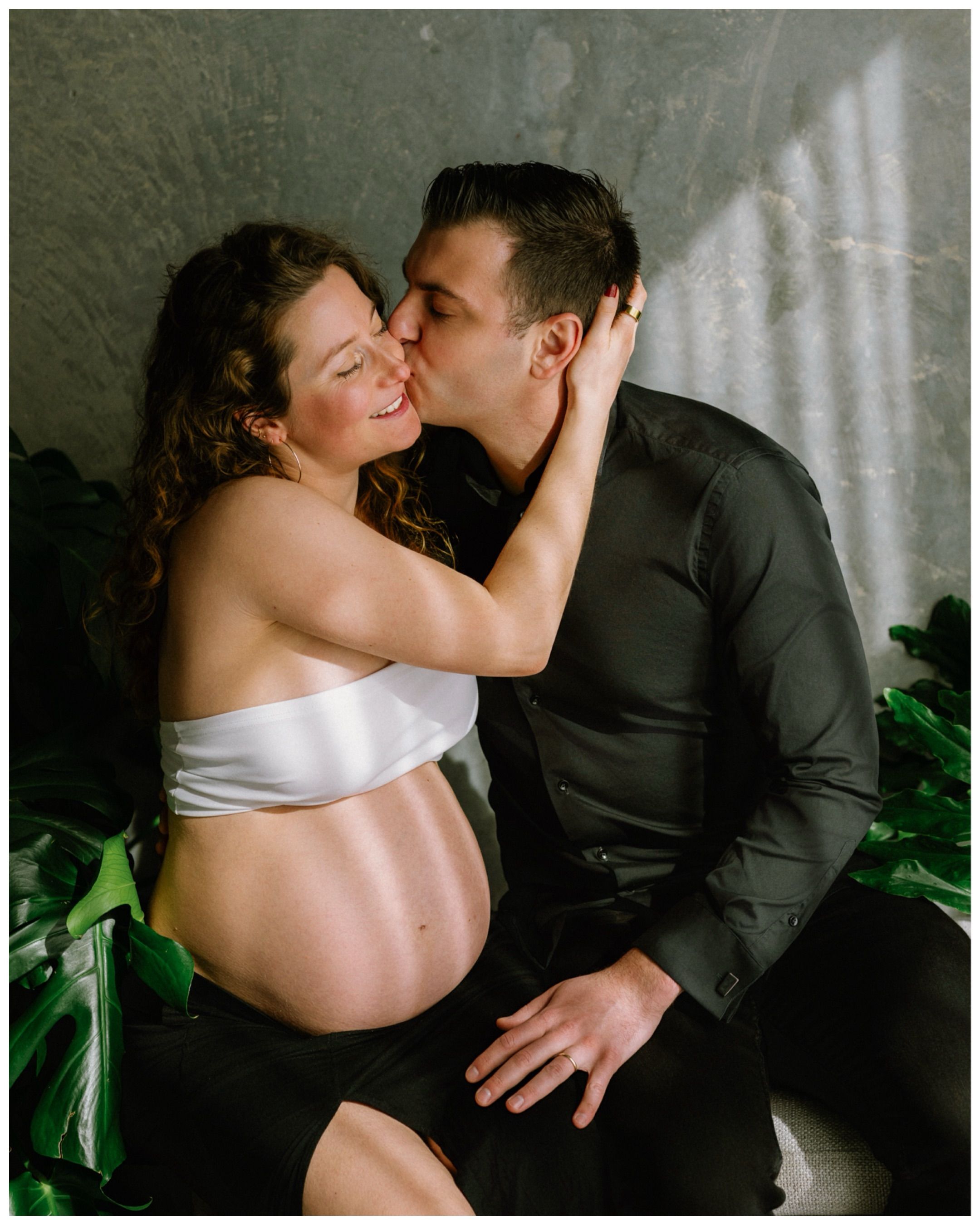 Expectant couple sharing a kiss during a studio maternity session