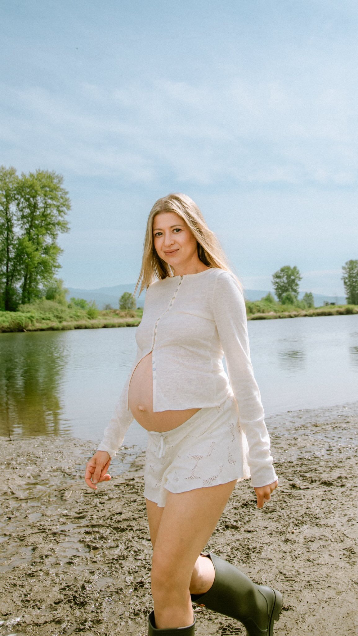 Expectant mother in white walking along a riverbank