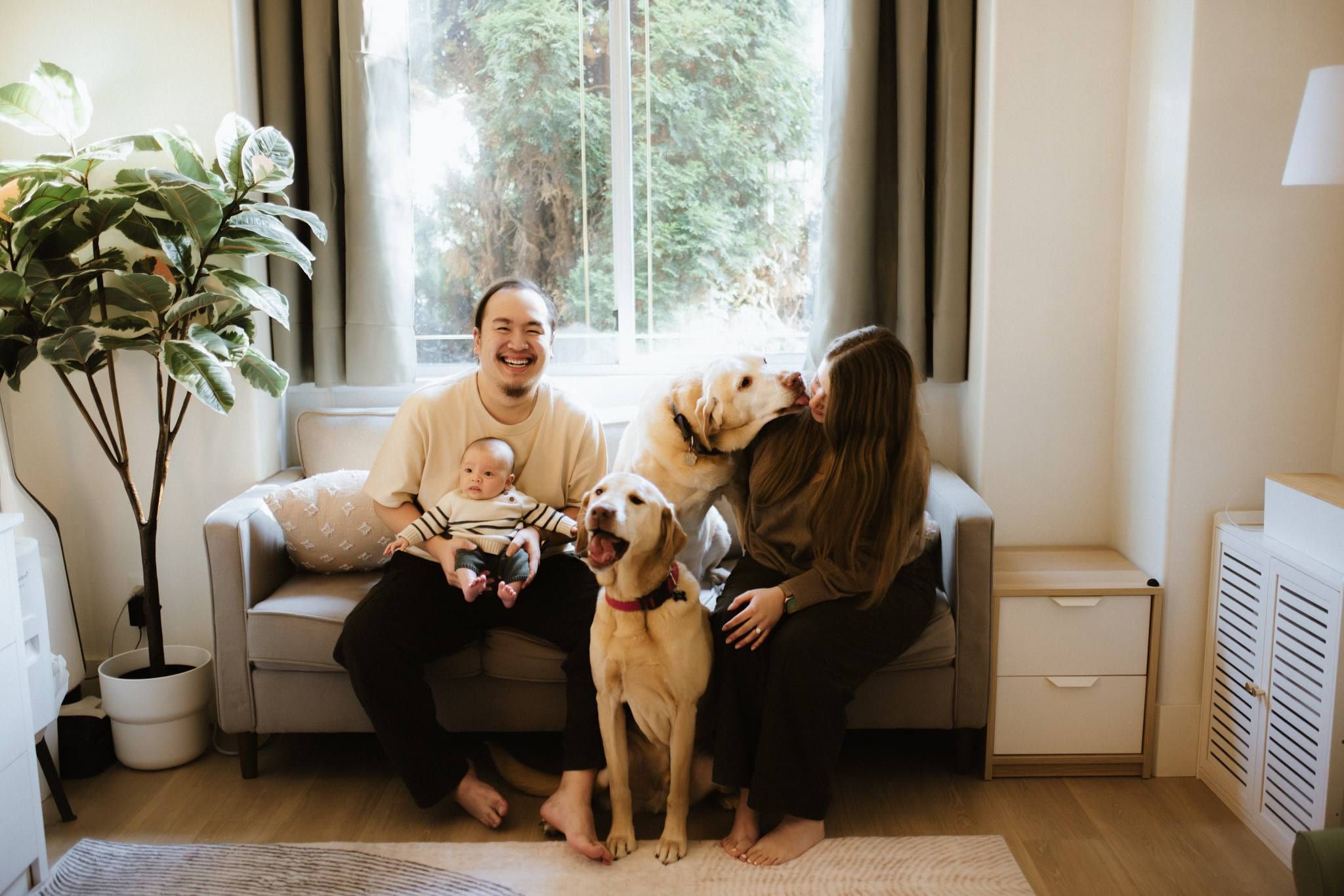 Family of three with their yellow labrador on a living-room sofa