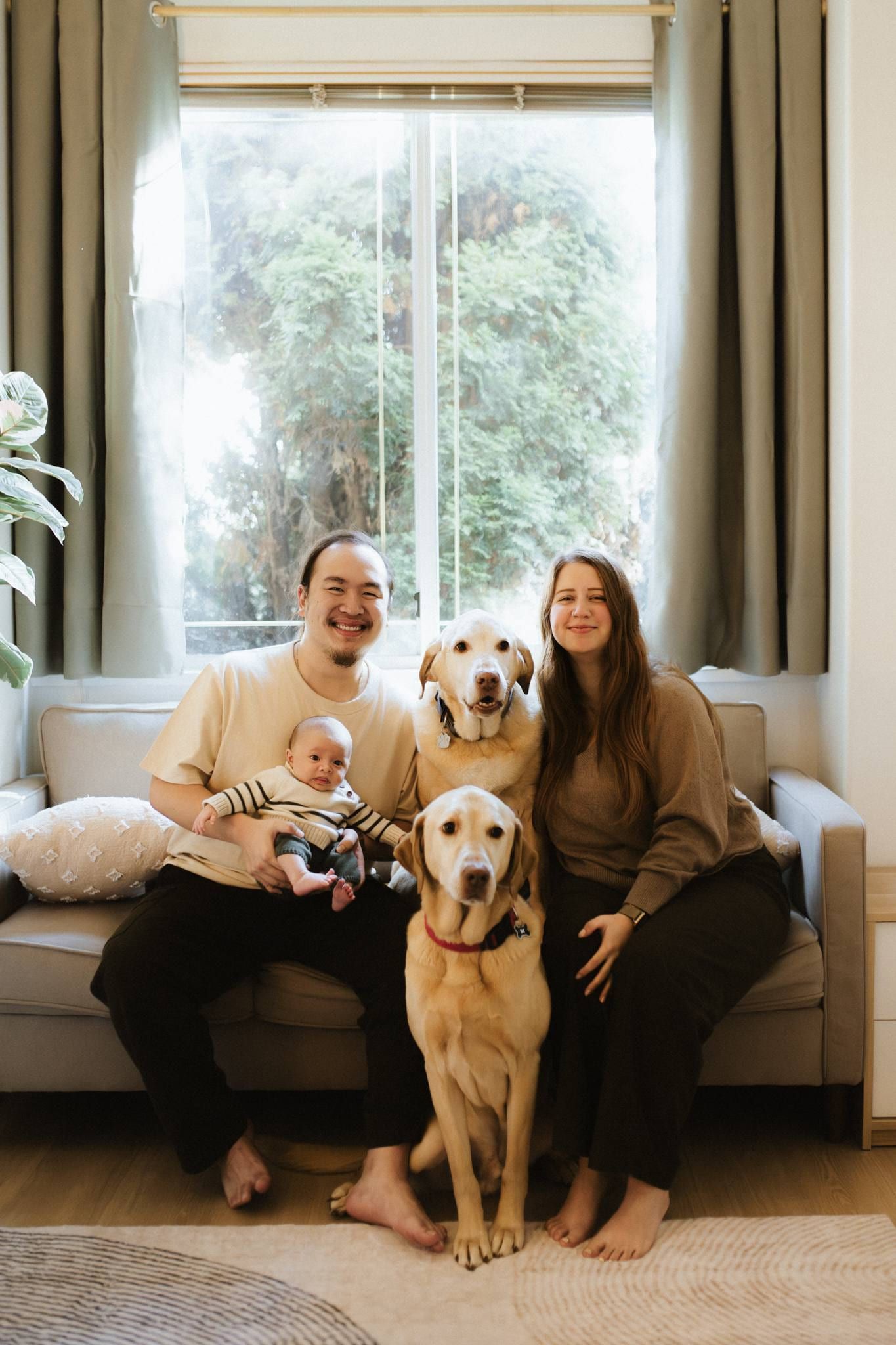 Family of three with their dog seated on a sofa in a bright living room