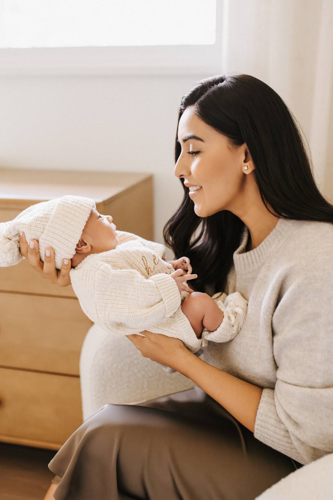 Mother smiling down at her newborn in a bright nursery