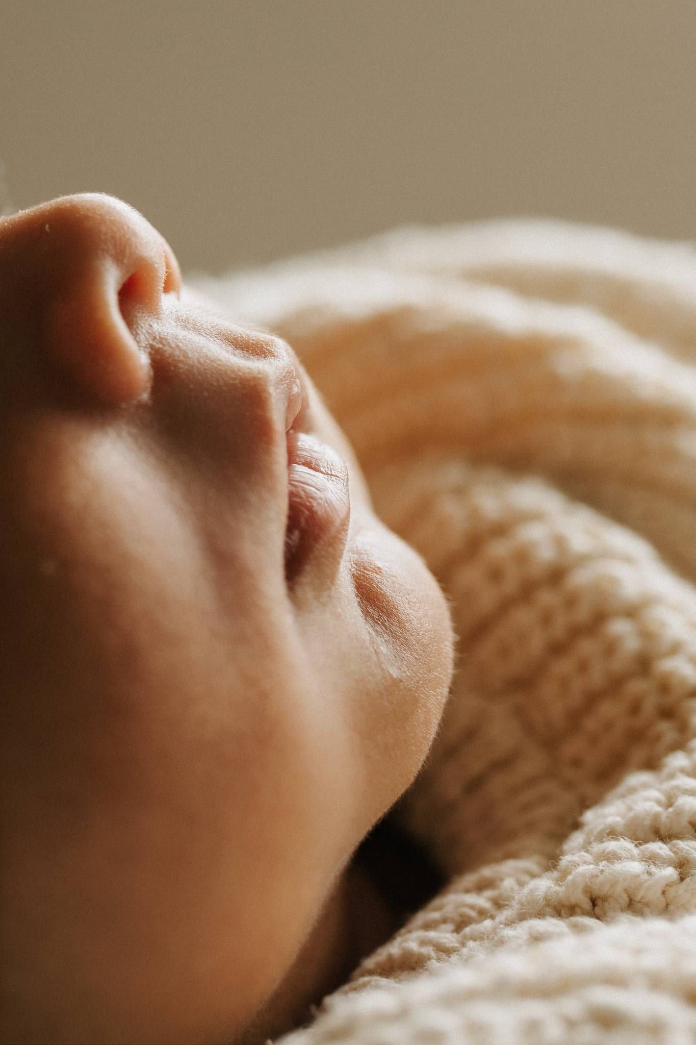 Close-up of a newborn's nose and lips against a knitted blanket
