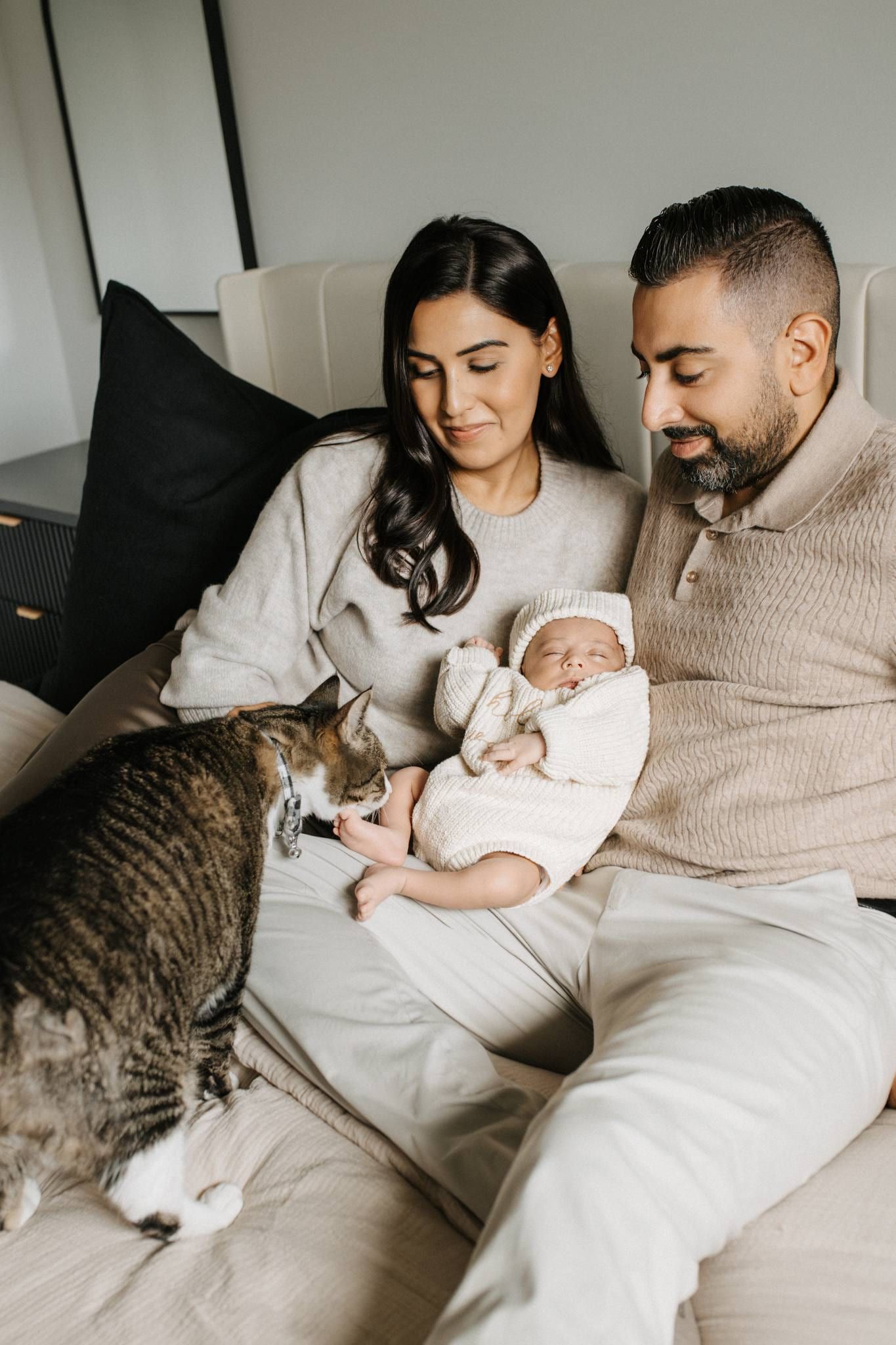 Parents on the bed with their newborn and the family cat