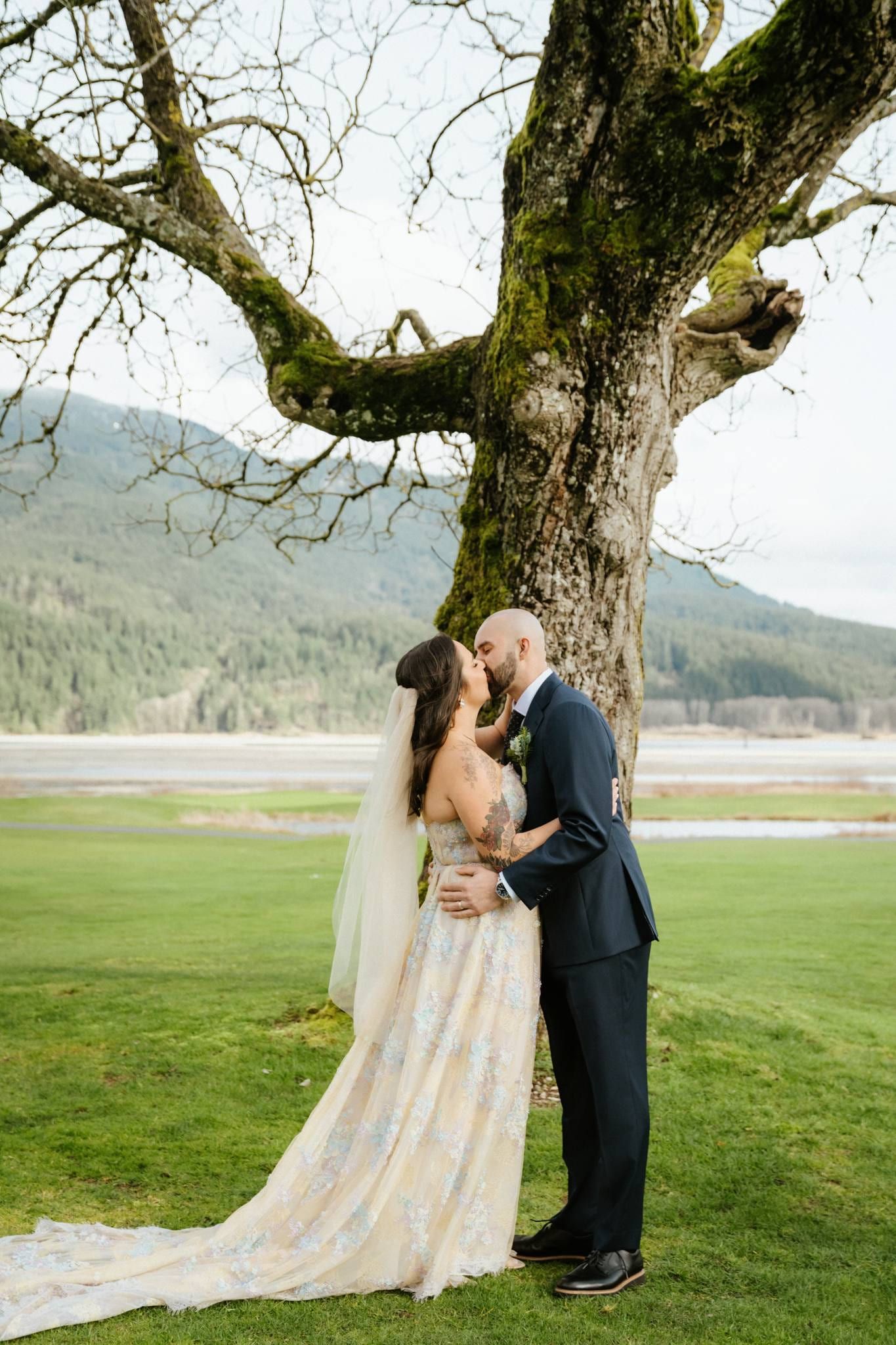 Couple embracing beneath the oak with mountains in the distance