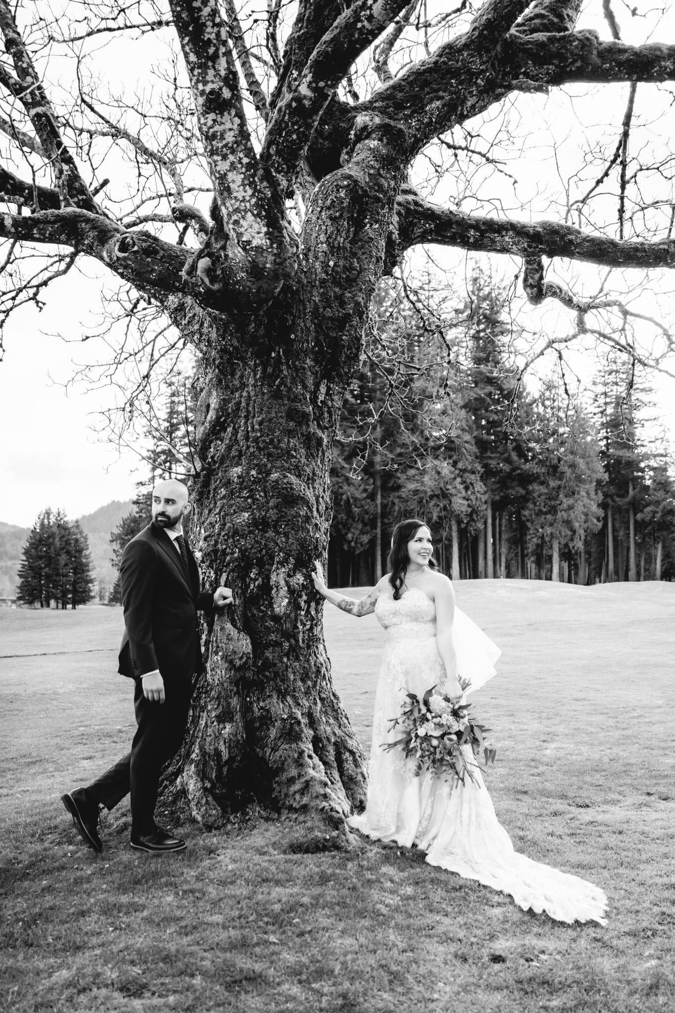 Black-and-white photo of the couple beside a huge mossy tree