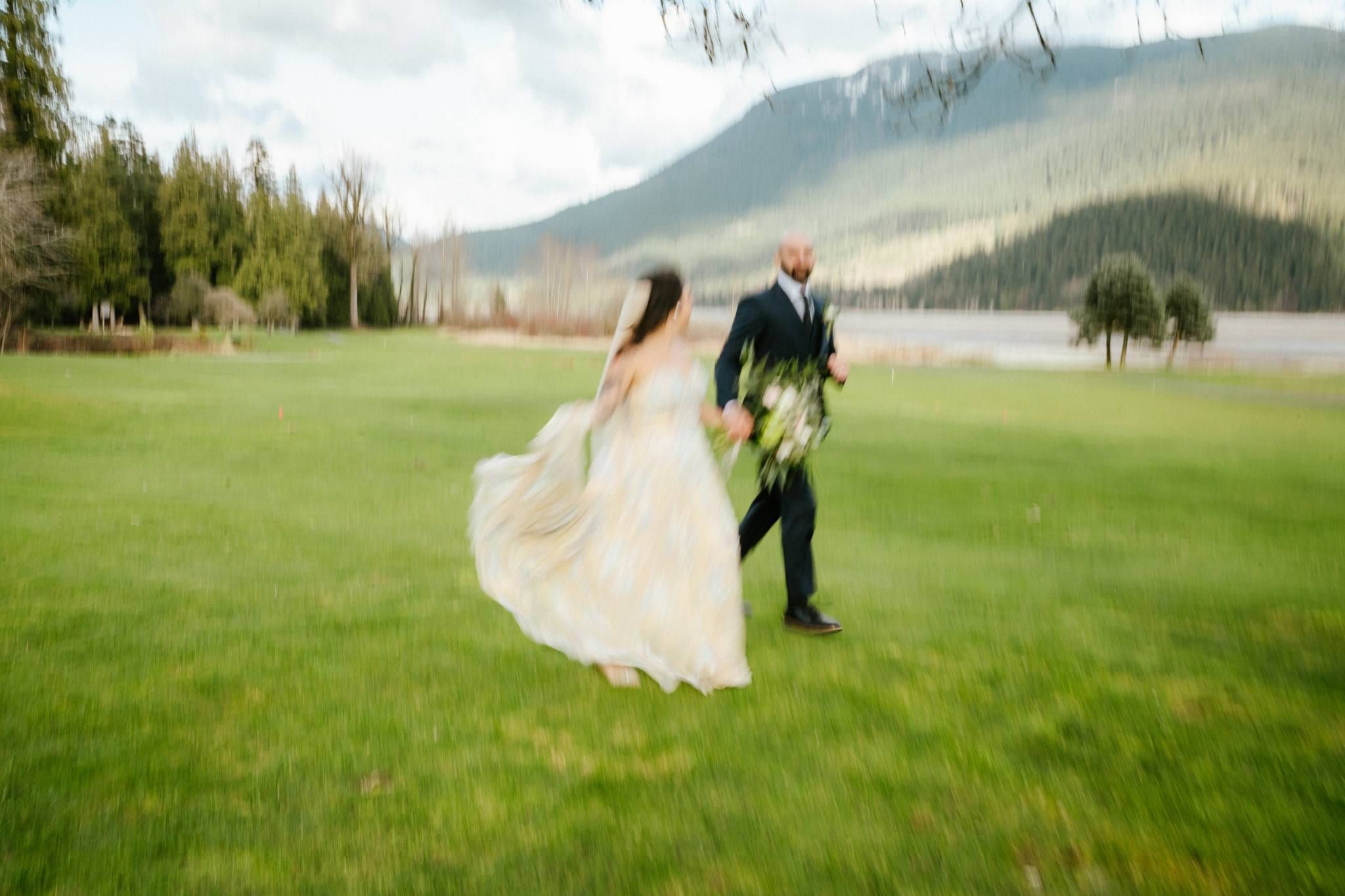 Bride and groom strolling across the fairway with mountains behind