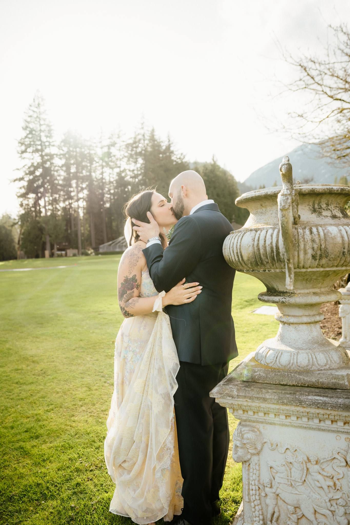 Couple embracing beside a stone urn on the lawn at dusk