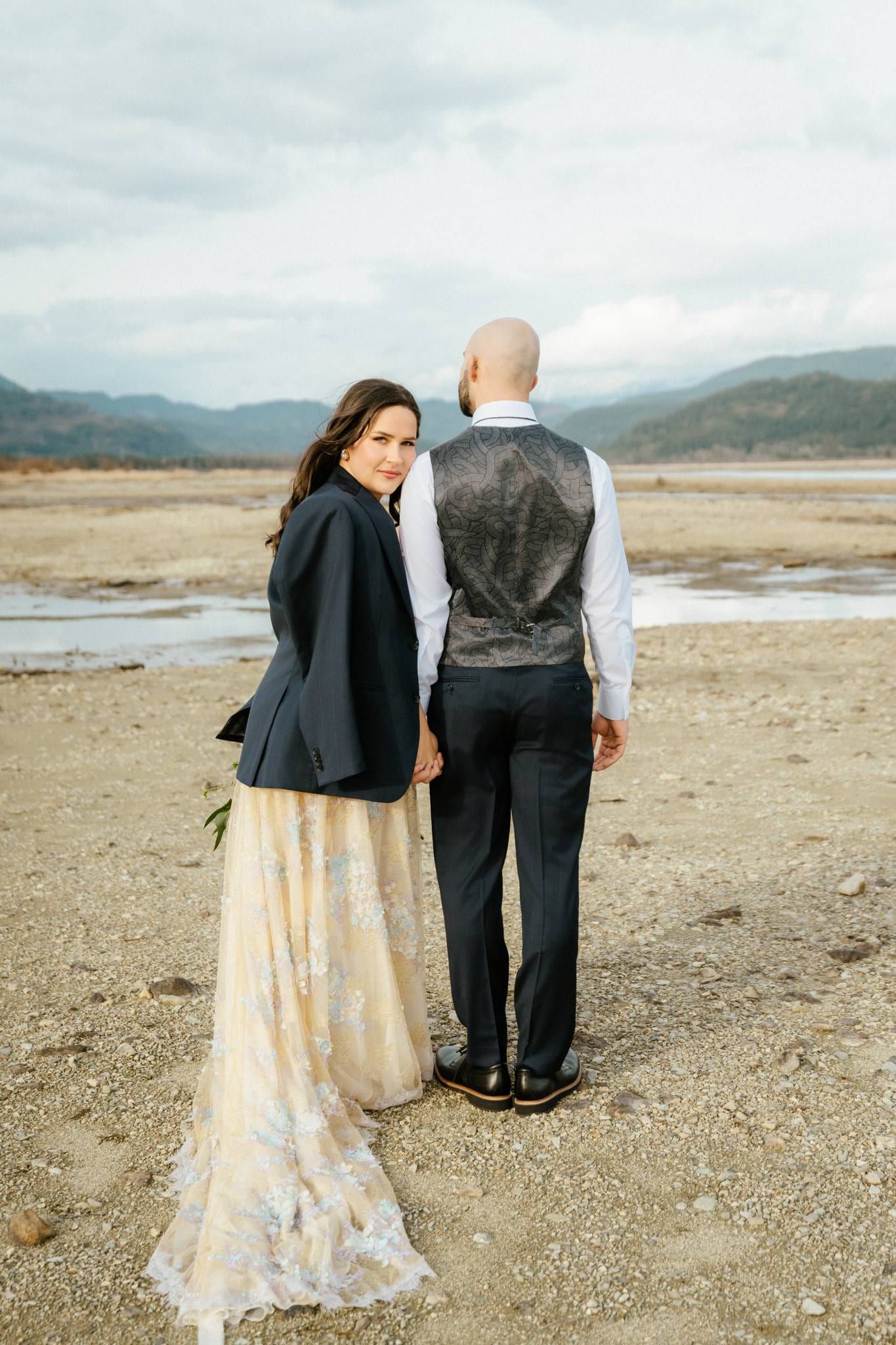 Couple seen from behind looking out over the riverbed and mountains