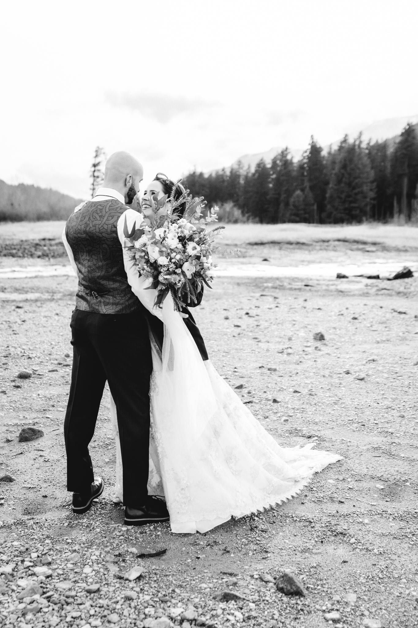 Black-and-white photo of the couple embracing on the riverbed