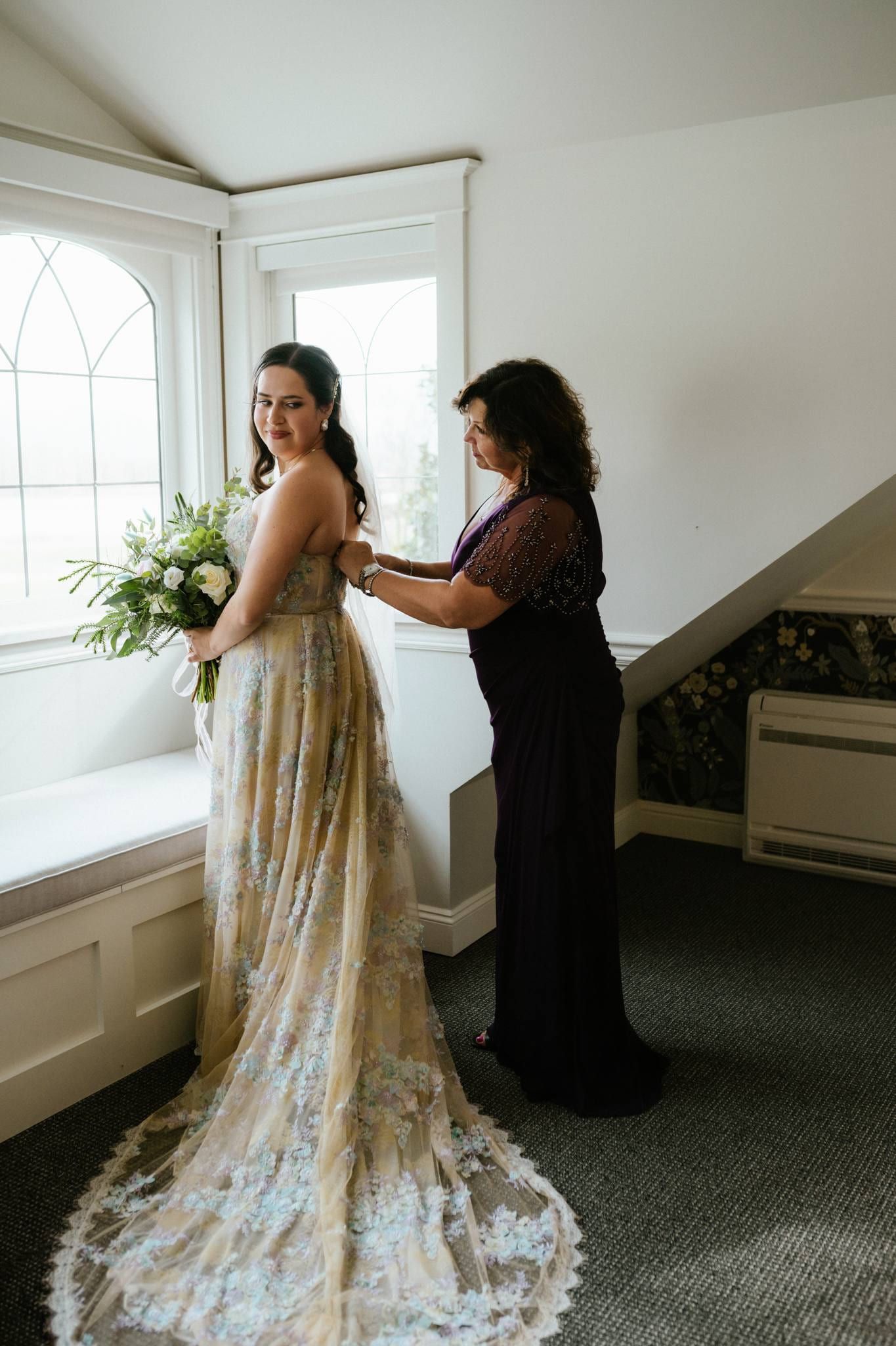 Bride's family helping with her veil and lace train by the window