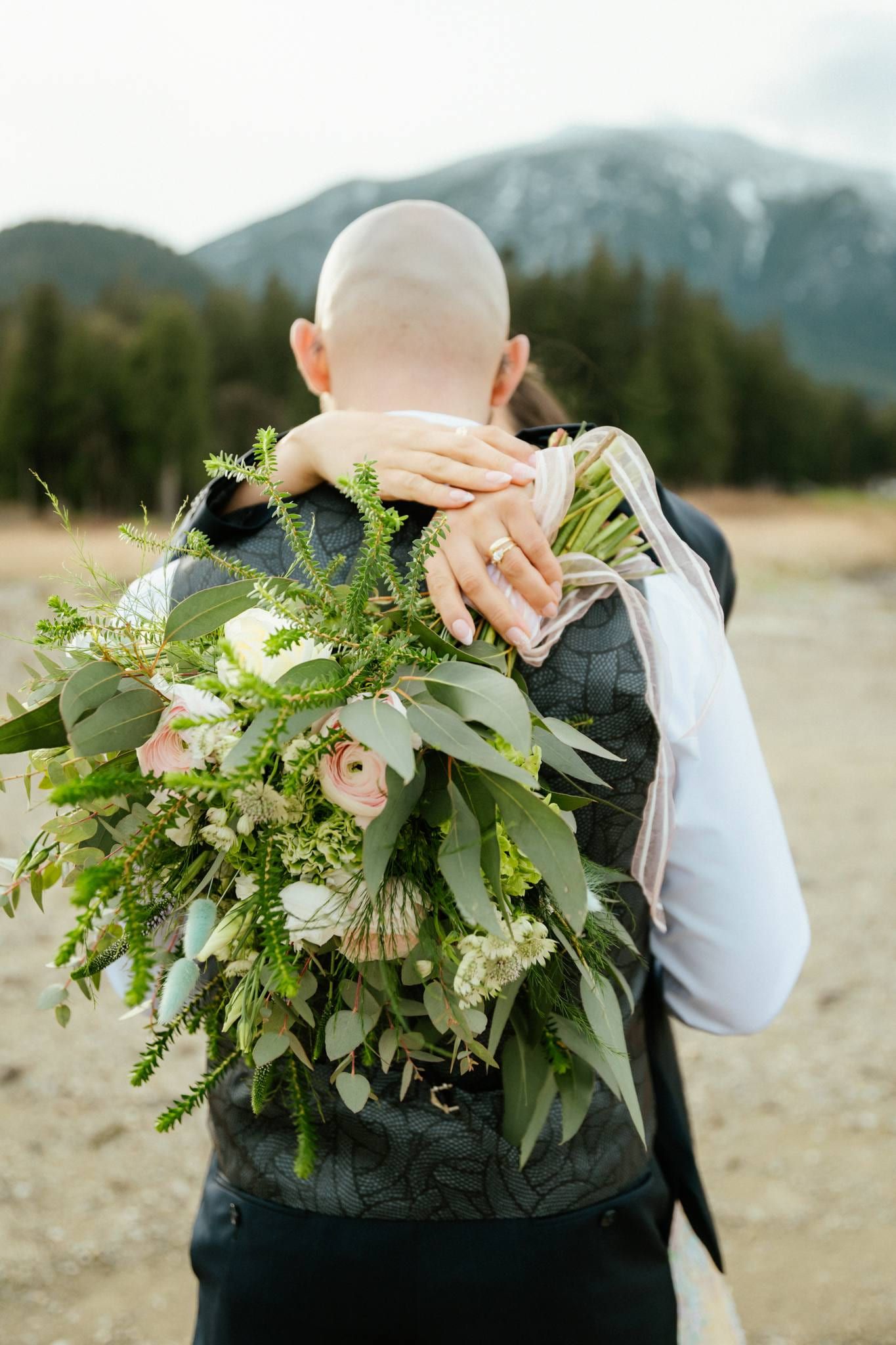Groom holding the bride, her bouquet over his shoulder, on the lawn