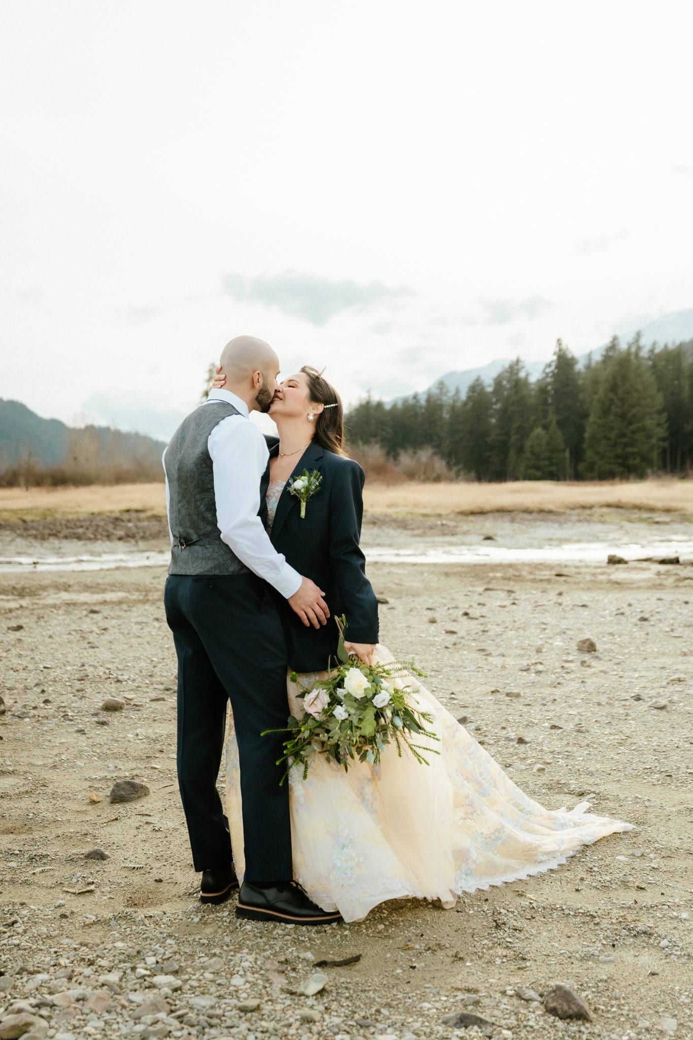 Couple kissing on the riverbed with mountains behind