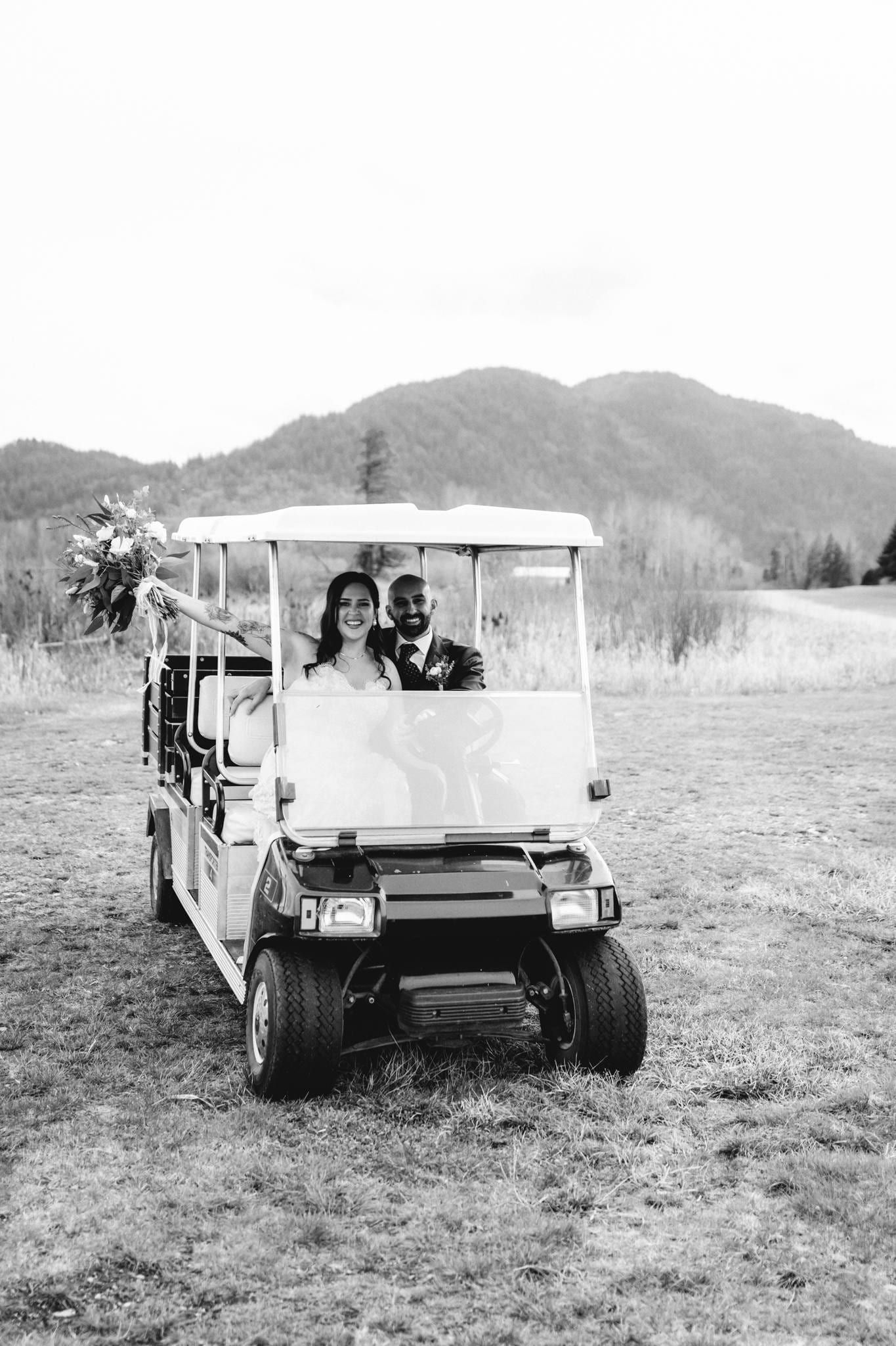 Black-and-white photo of the couple riding a golf cart across the course