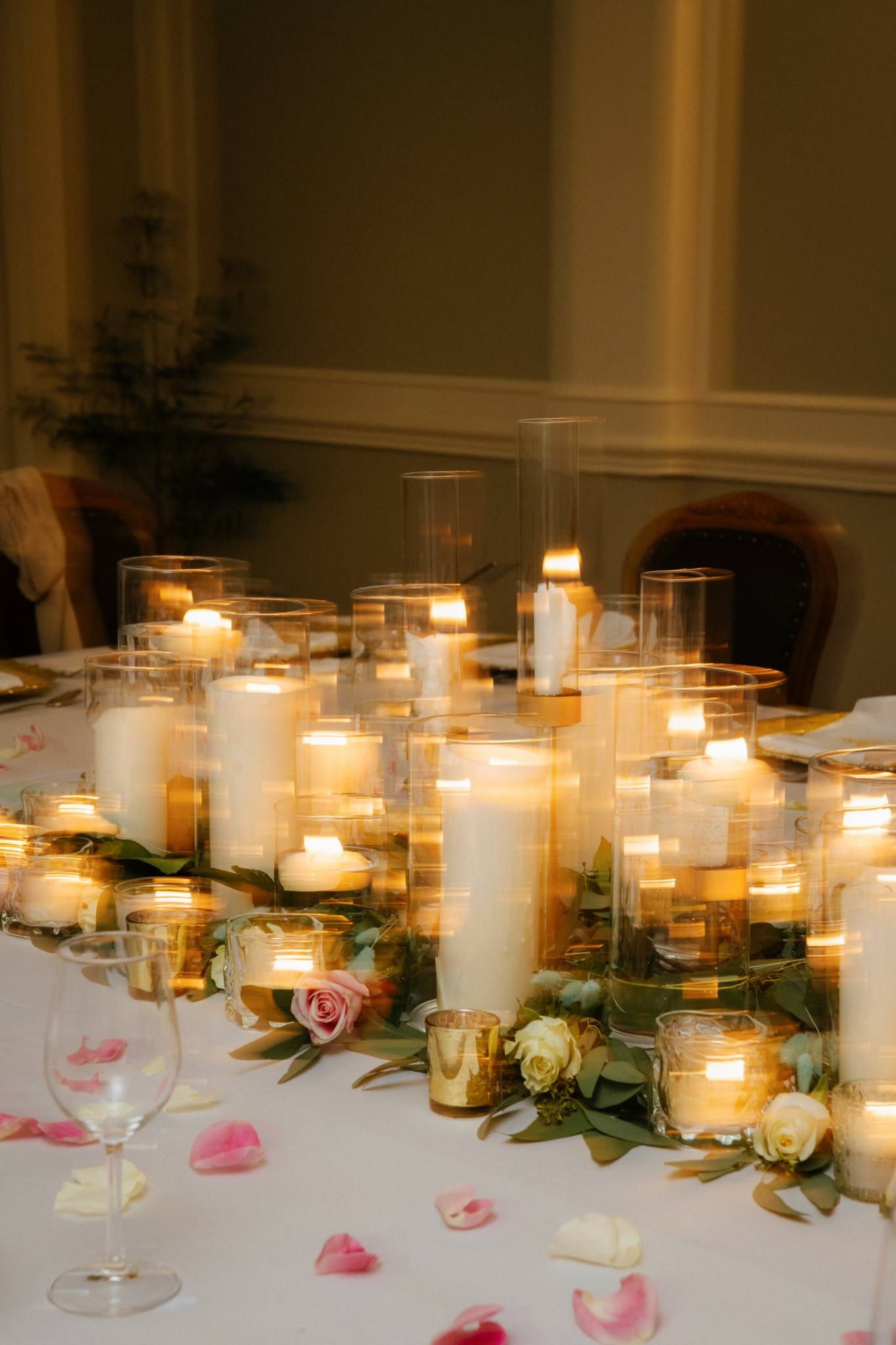Pillar candles and petals glowing on the reception table