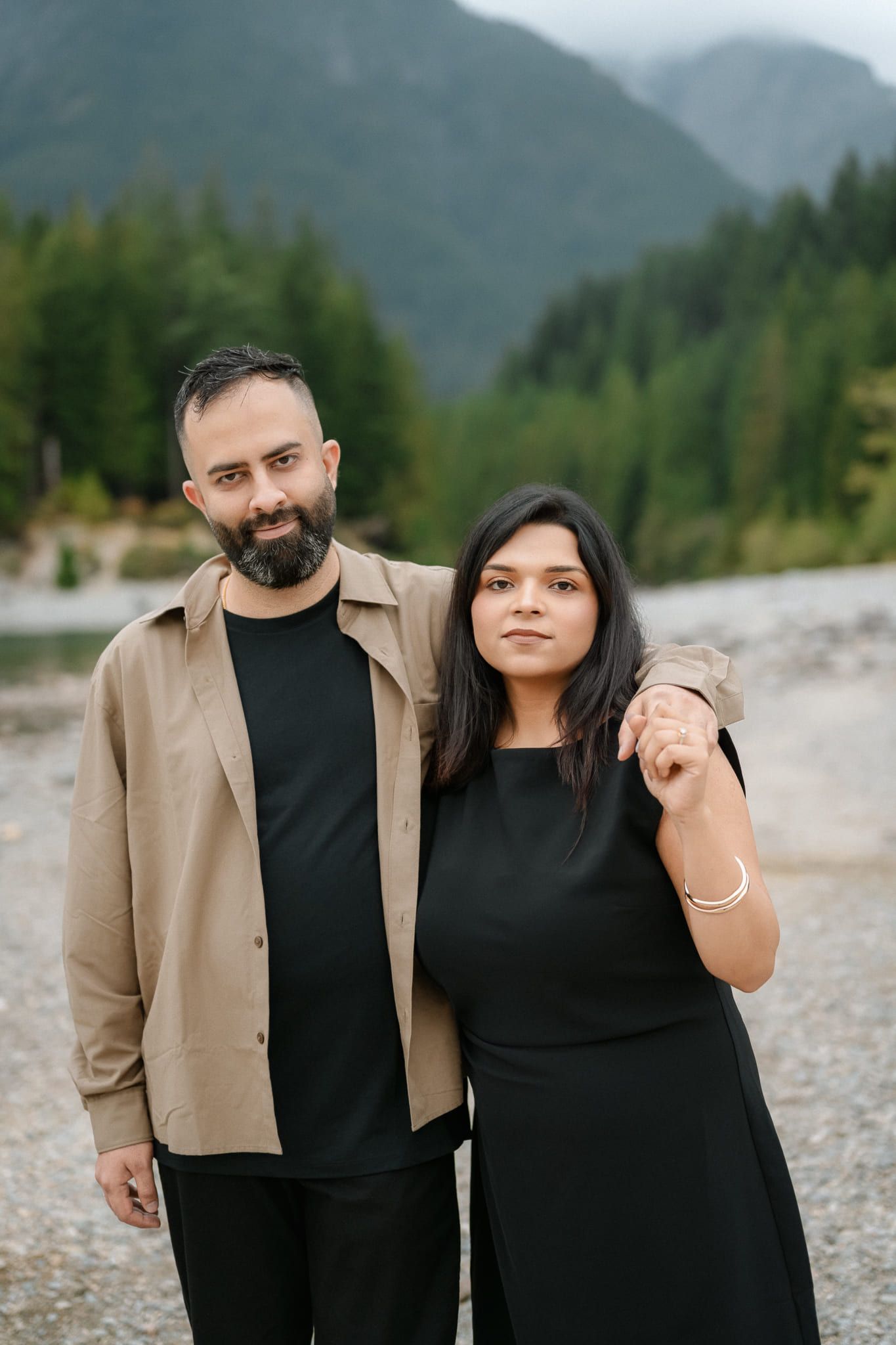 Creative engagement photography, couple embracing on a river beach surrounded by forest