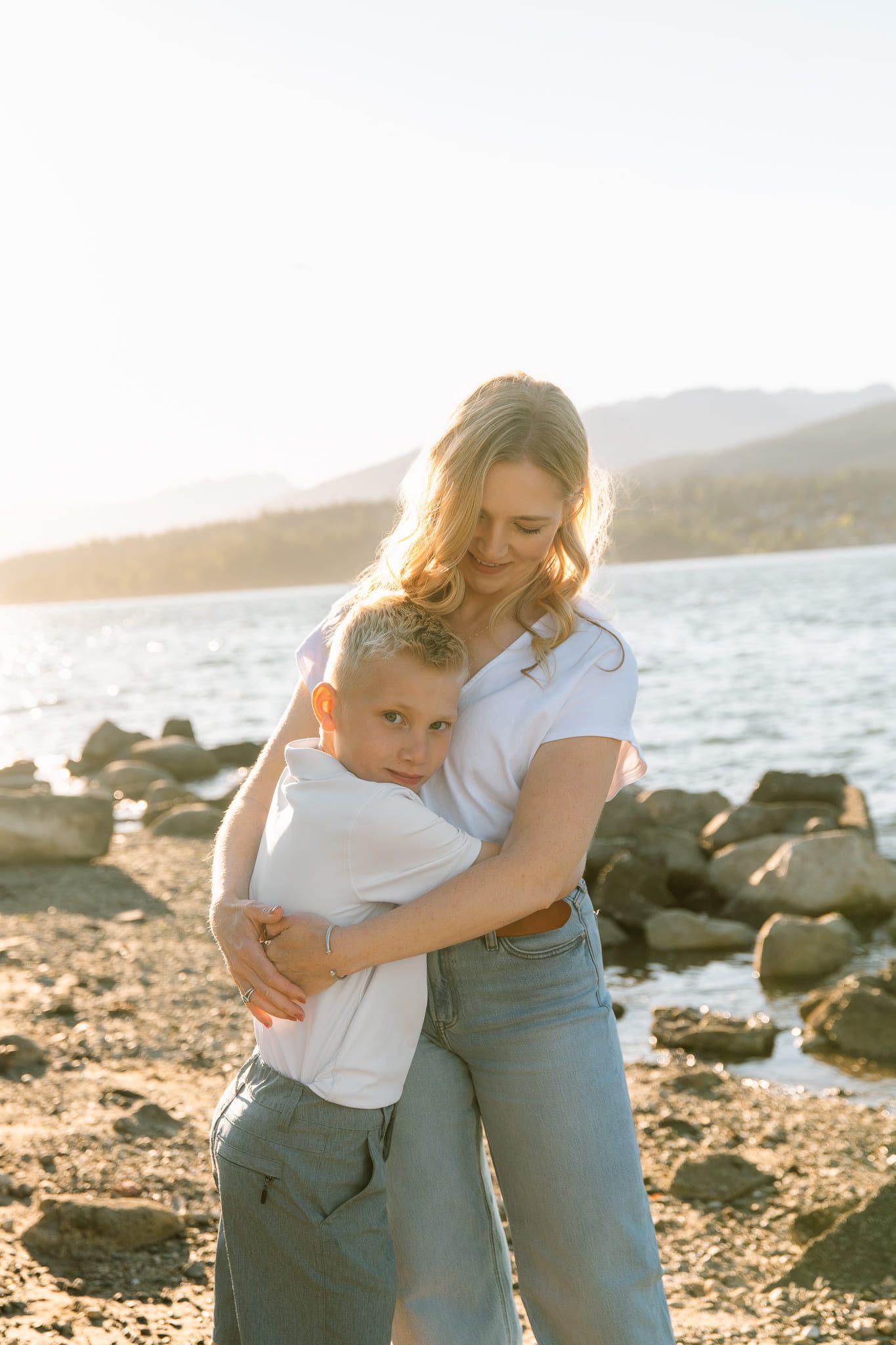 Sunset family photography on the rocky shore, mother hugging her son