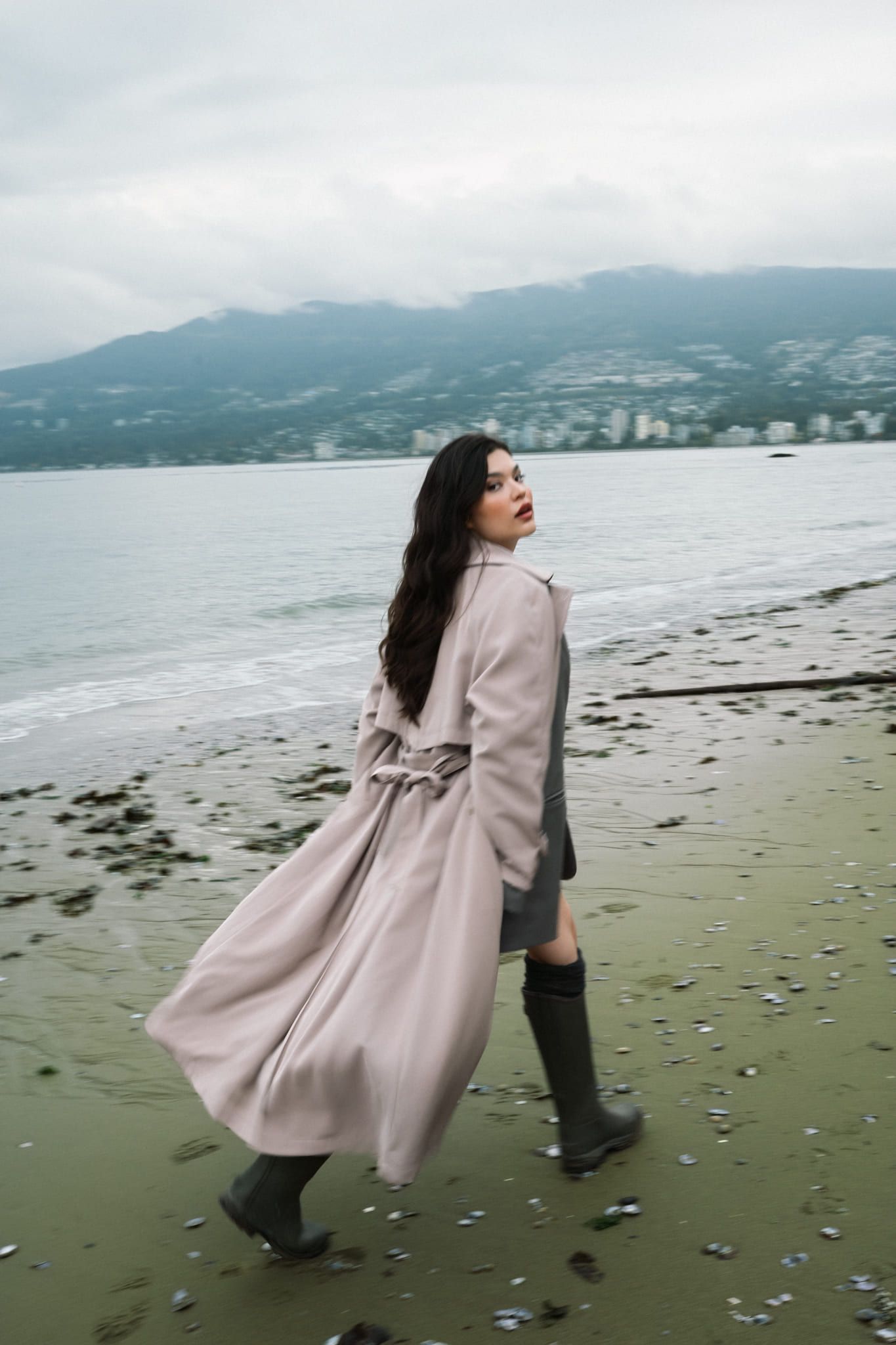 Beach portrait photo at low tide, woman in a long coat walking along the beach
