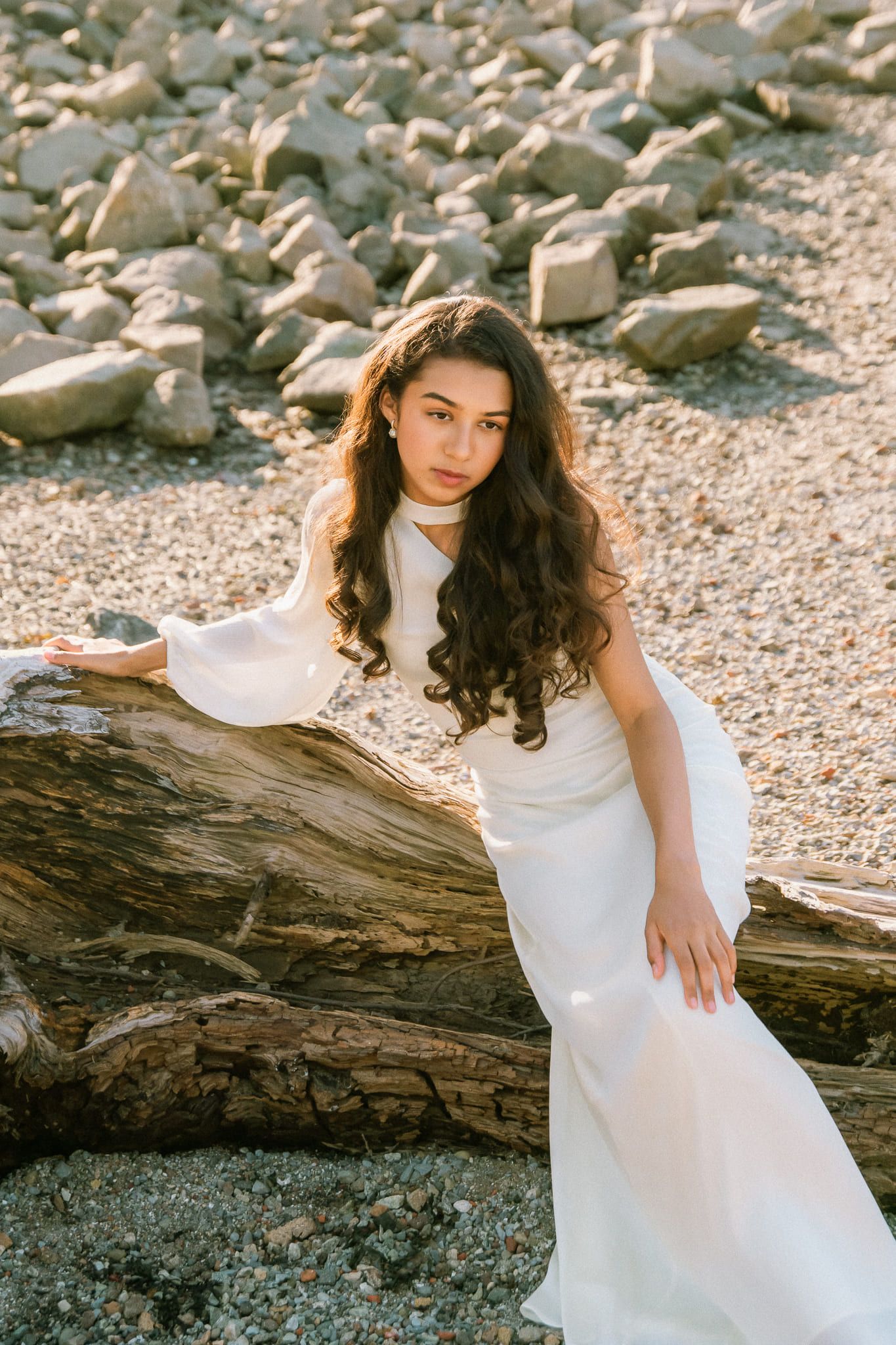 Moody portrait photography on the beach at sunset, young woman in a white gown