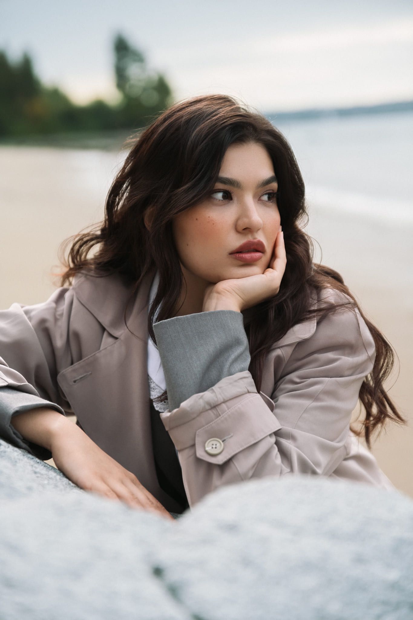 Beach portrait photography, woman in a coat resting her chin on her hand