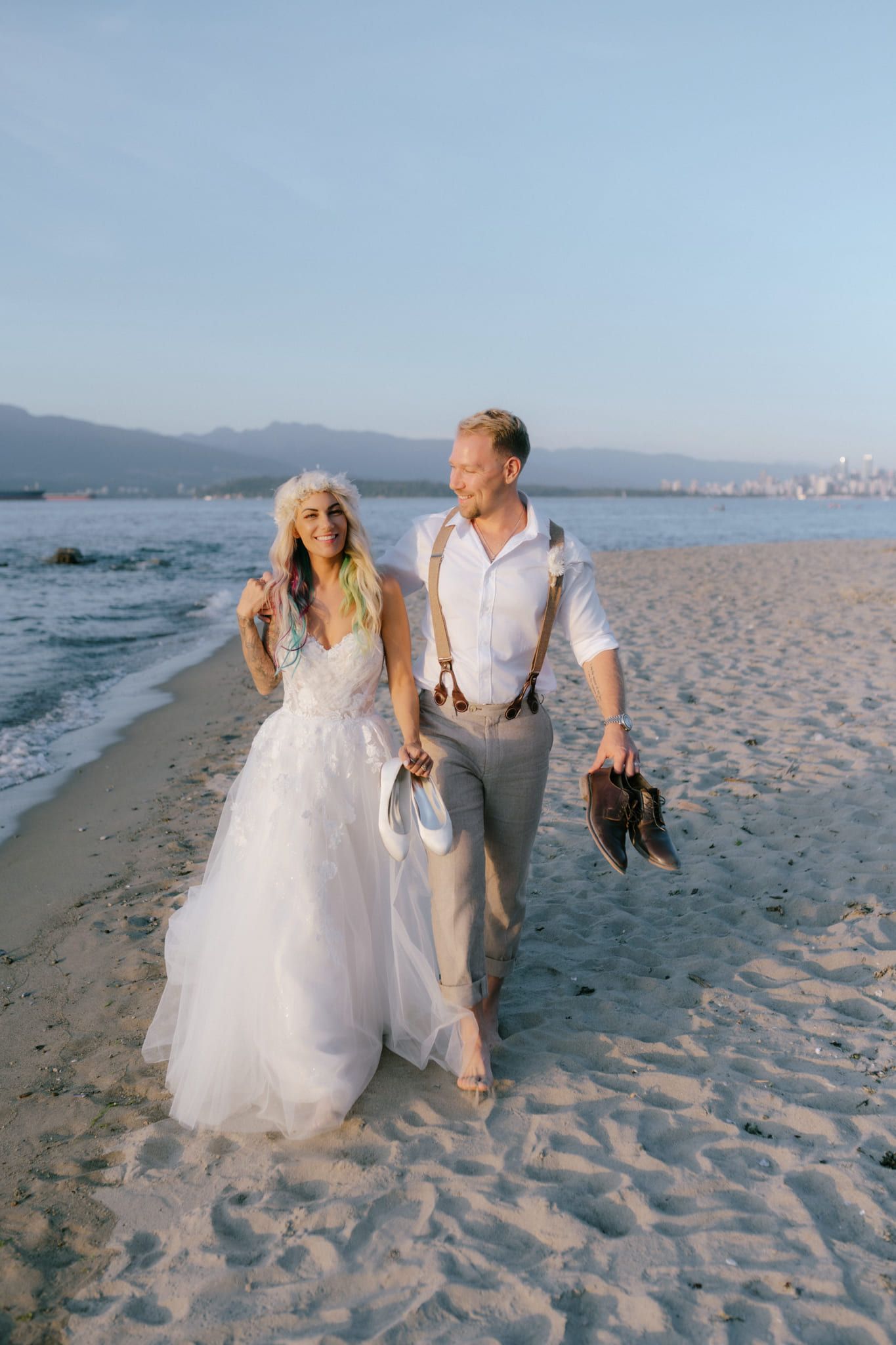 Lifestyle wedding photography along the beach at sunset, bride and groom walking barefoot