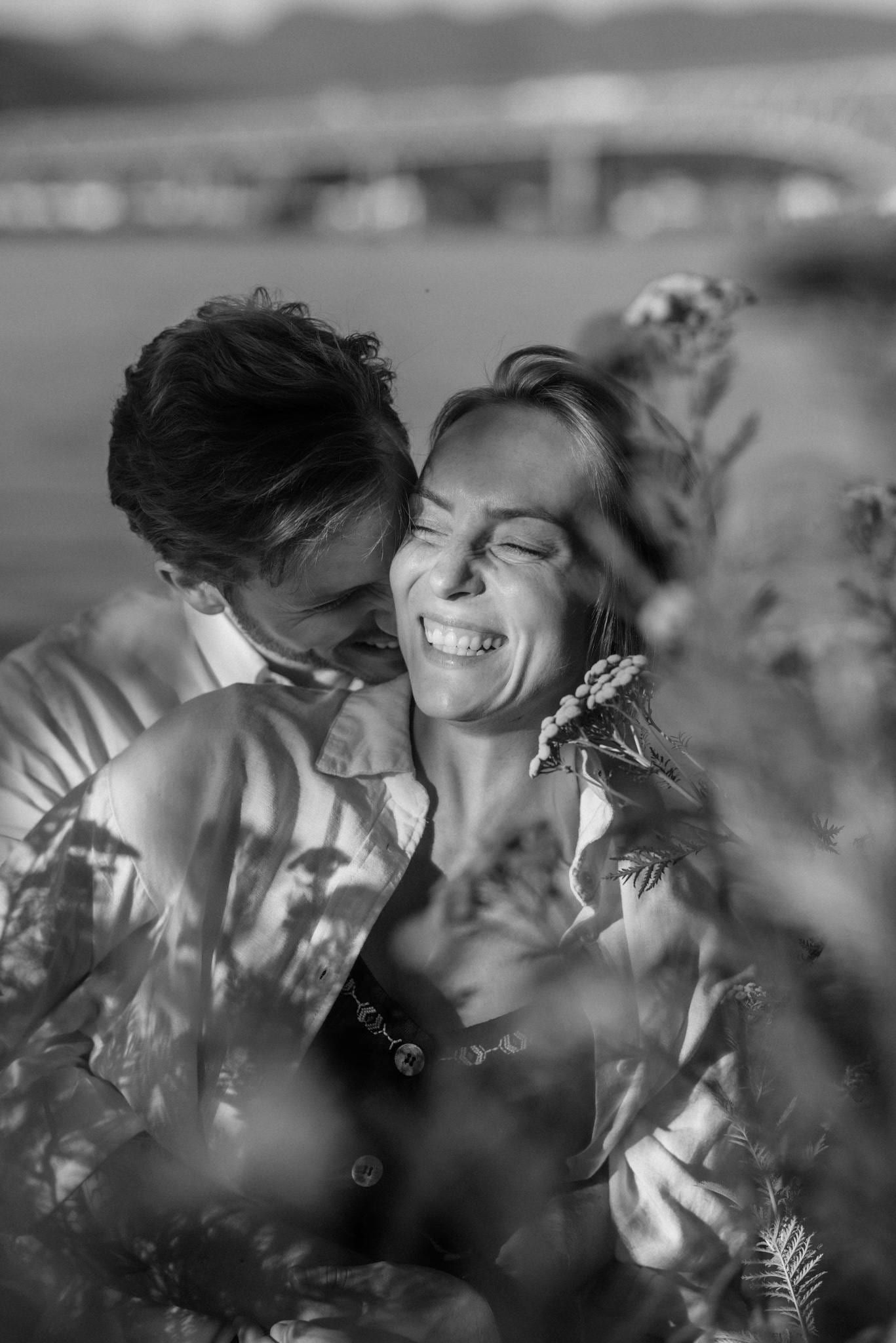 Candid engagement photos among leaves, black-and-white photo of a laughing couple