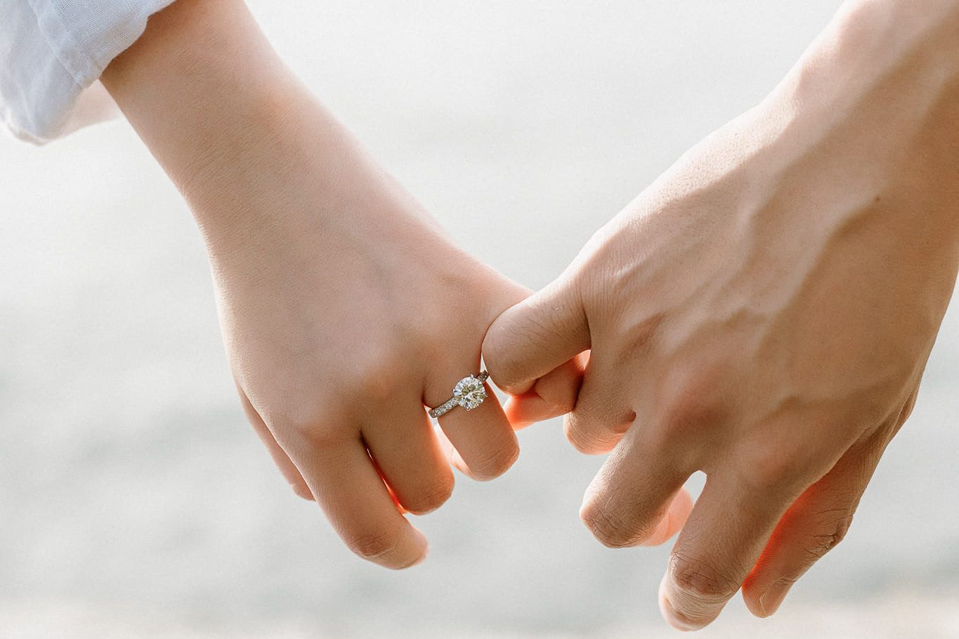 Natural engagement photos, close-up of a couple holding hands, an engagement ring on her finger