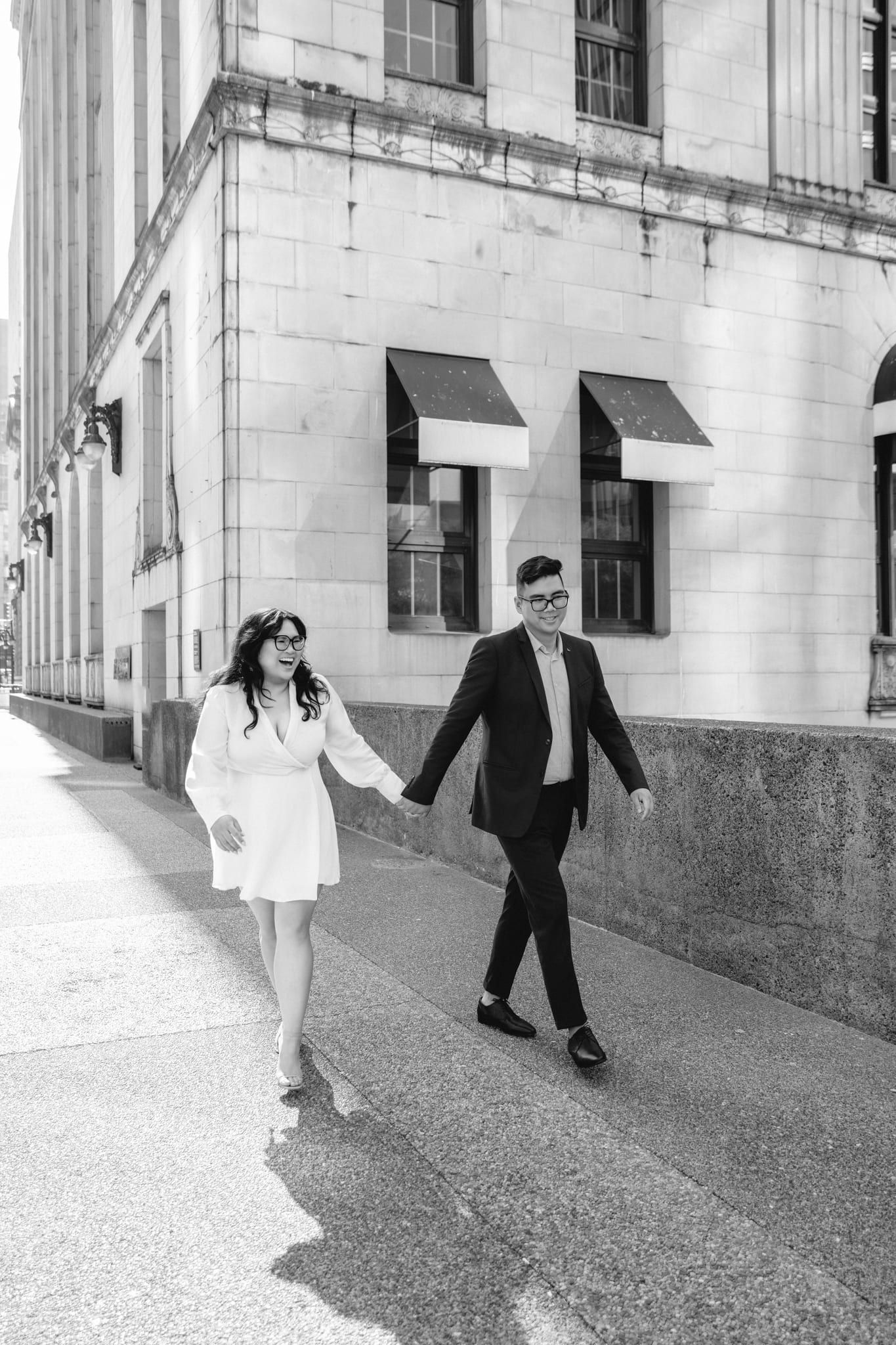 Downtown couple photoshoot, black-and-white photo of a couple walking hand