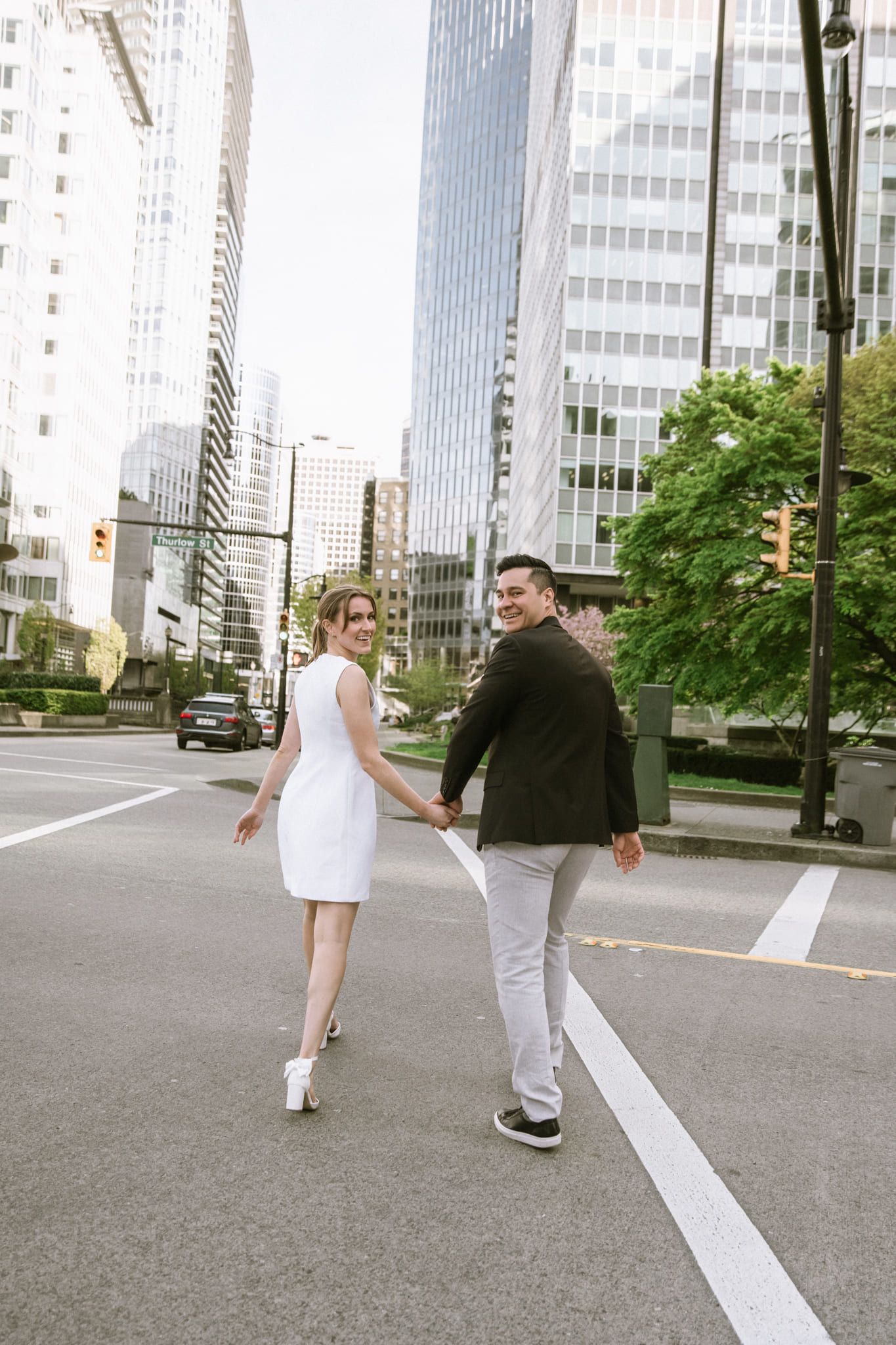 Professional engagement photos among downtown towers, couple in white and black