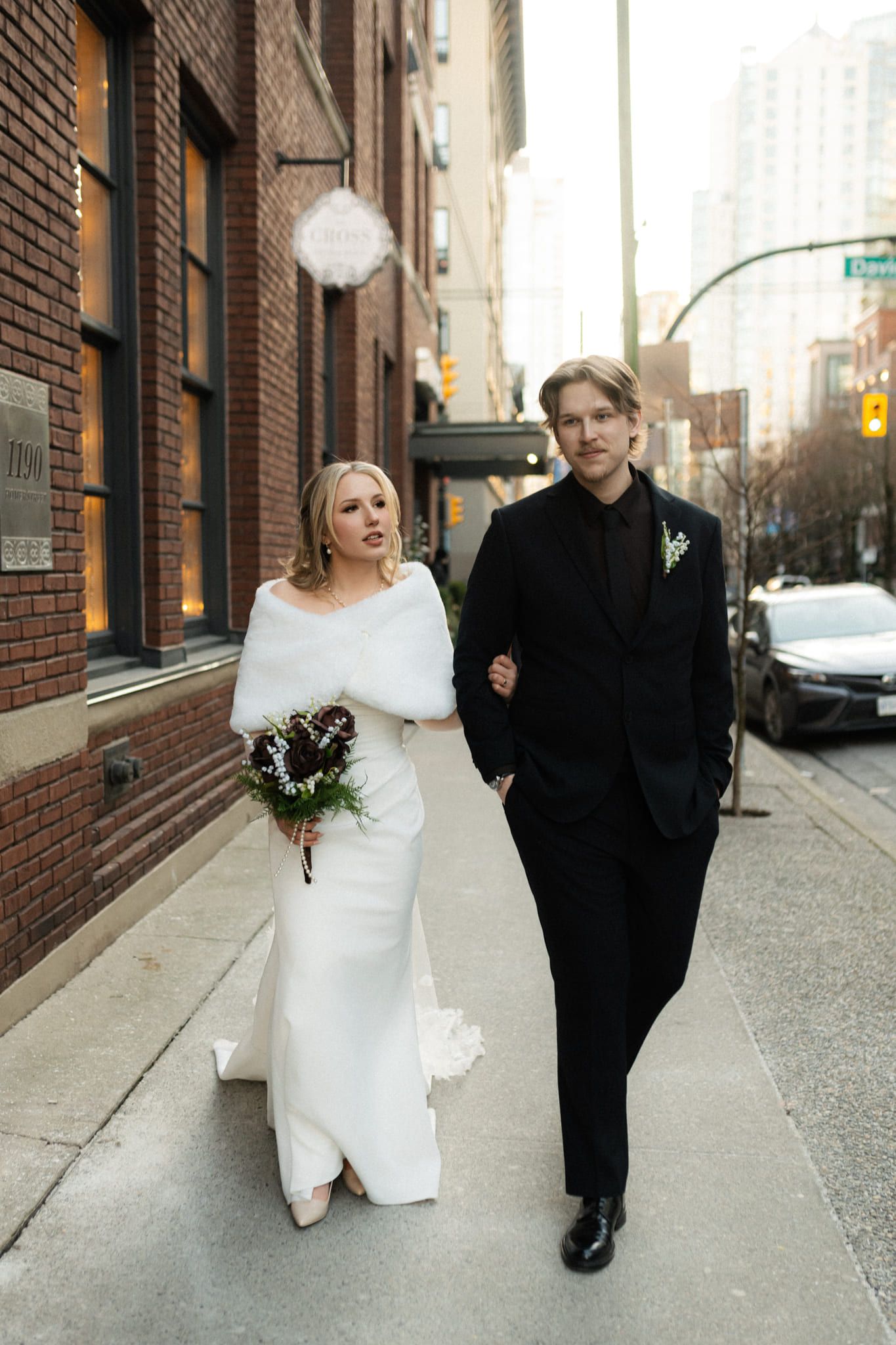 Creative wedding photos, bride in a white wrap and groom walking along a city street