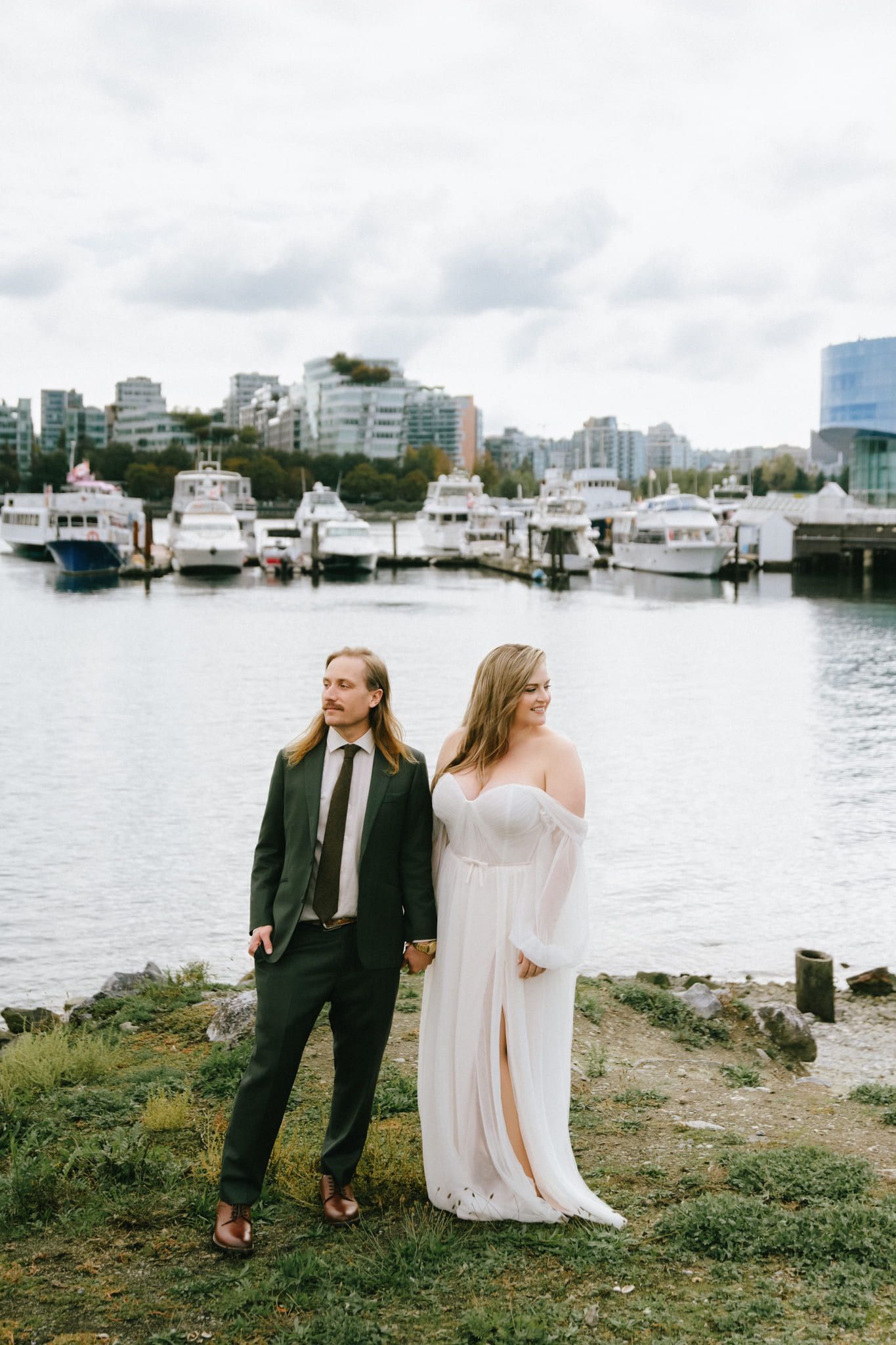 Classic wedding photos, bride and groom by the water with downtown towers behind