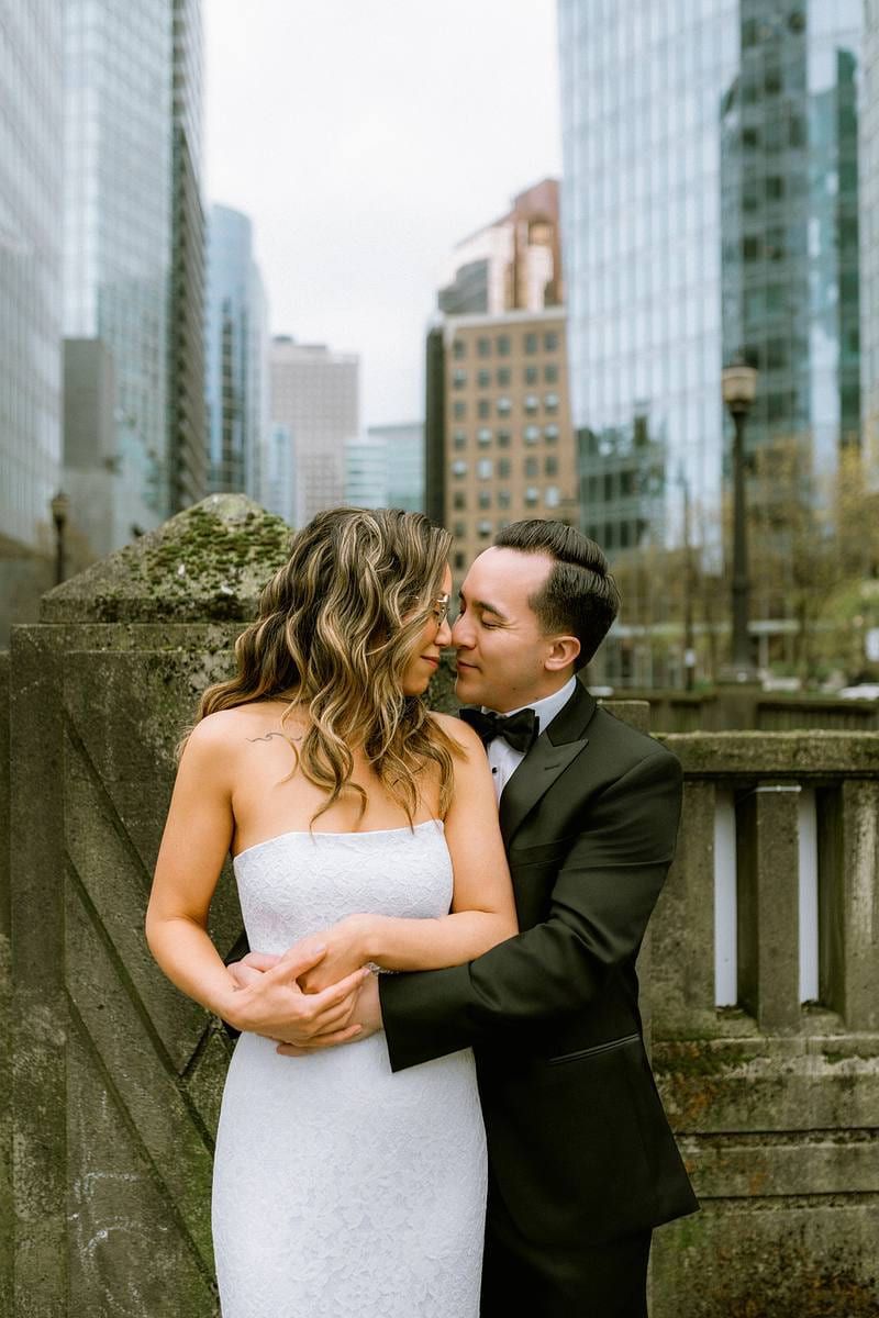 Natural wedding photography, couple embracing on a rooftop terrace with downtown towers behind
