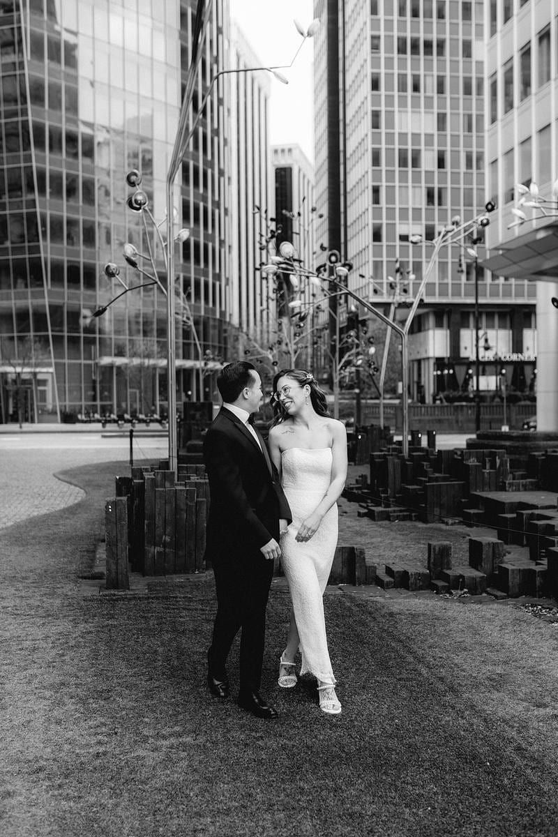 Black and white wedding photography in hand between downtown towers, the couple walking hand