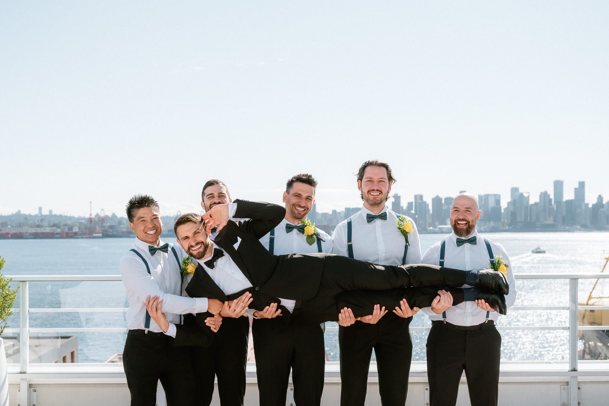Intimate wedding photos in front of the city skyline, groomsmen lifting the groom