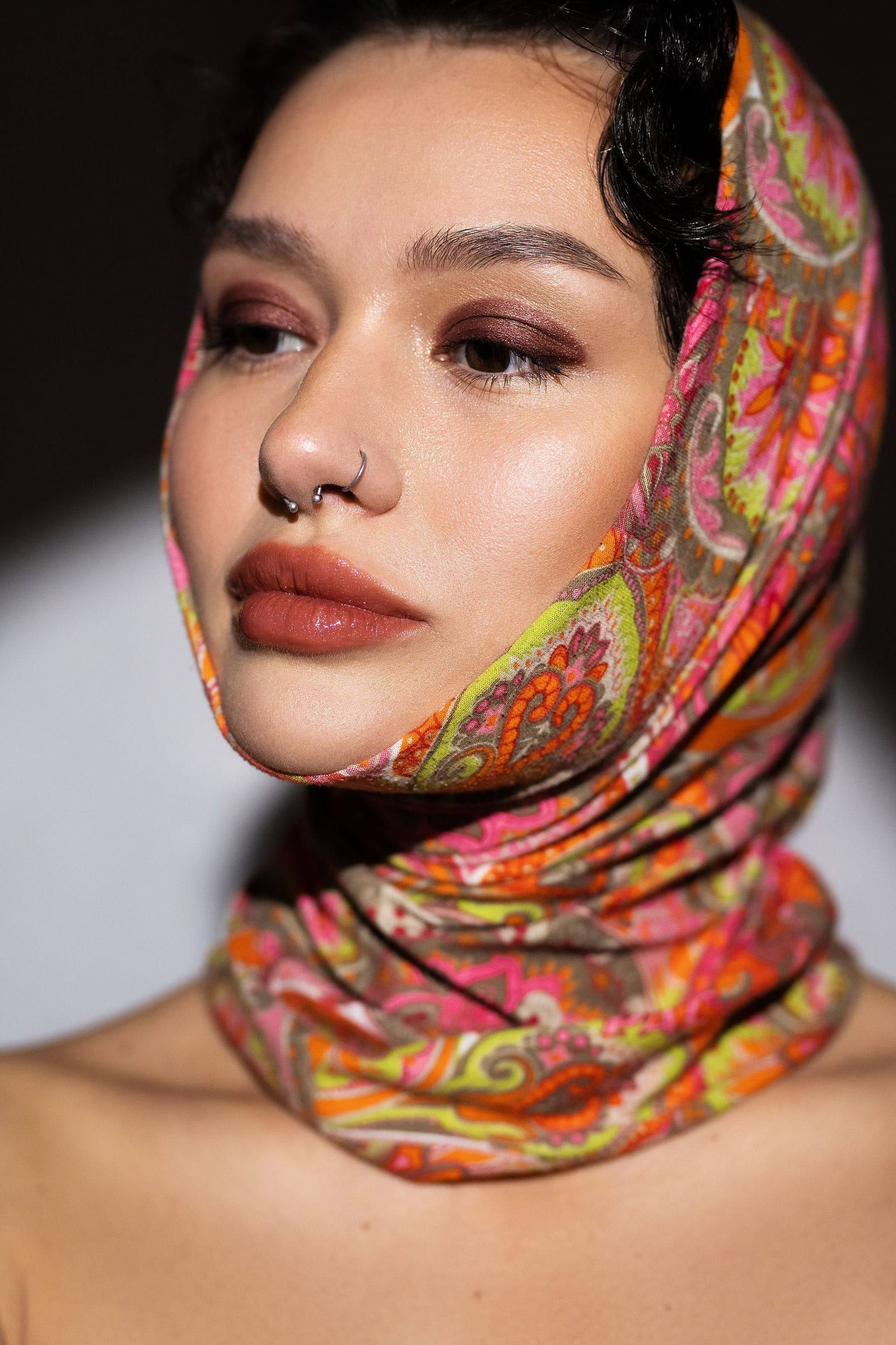 Model in a bright paisley headscarf looking down