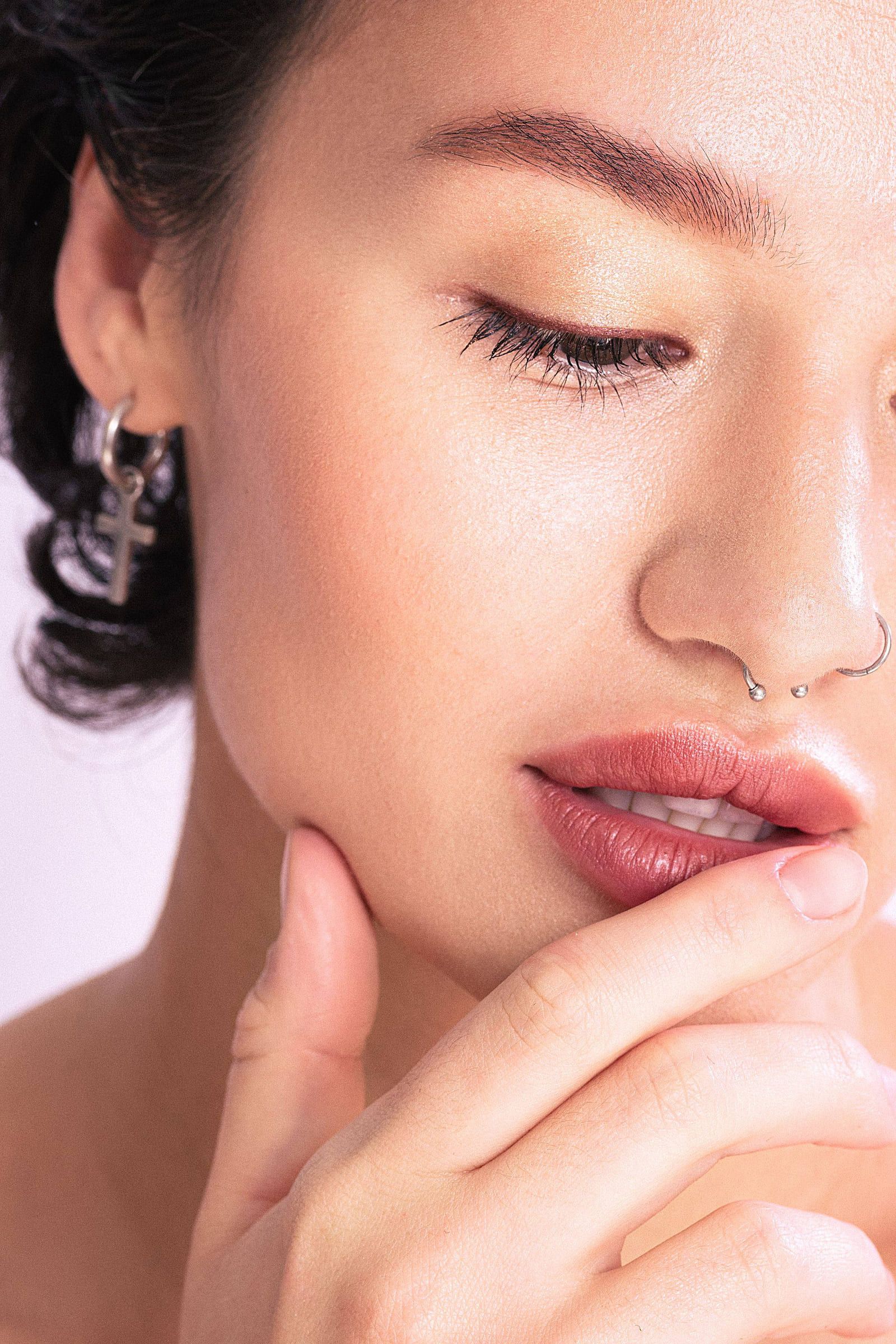 Beauty close-up of a model's lips and hand in soft pink light