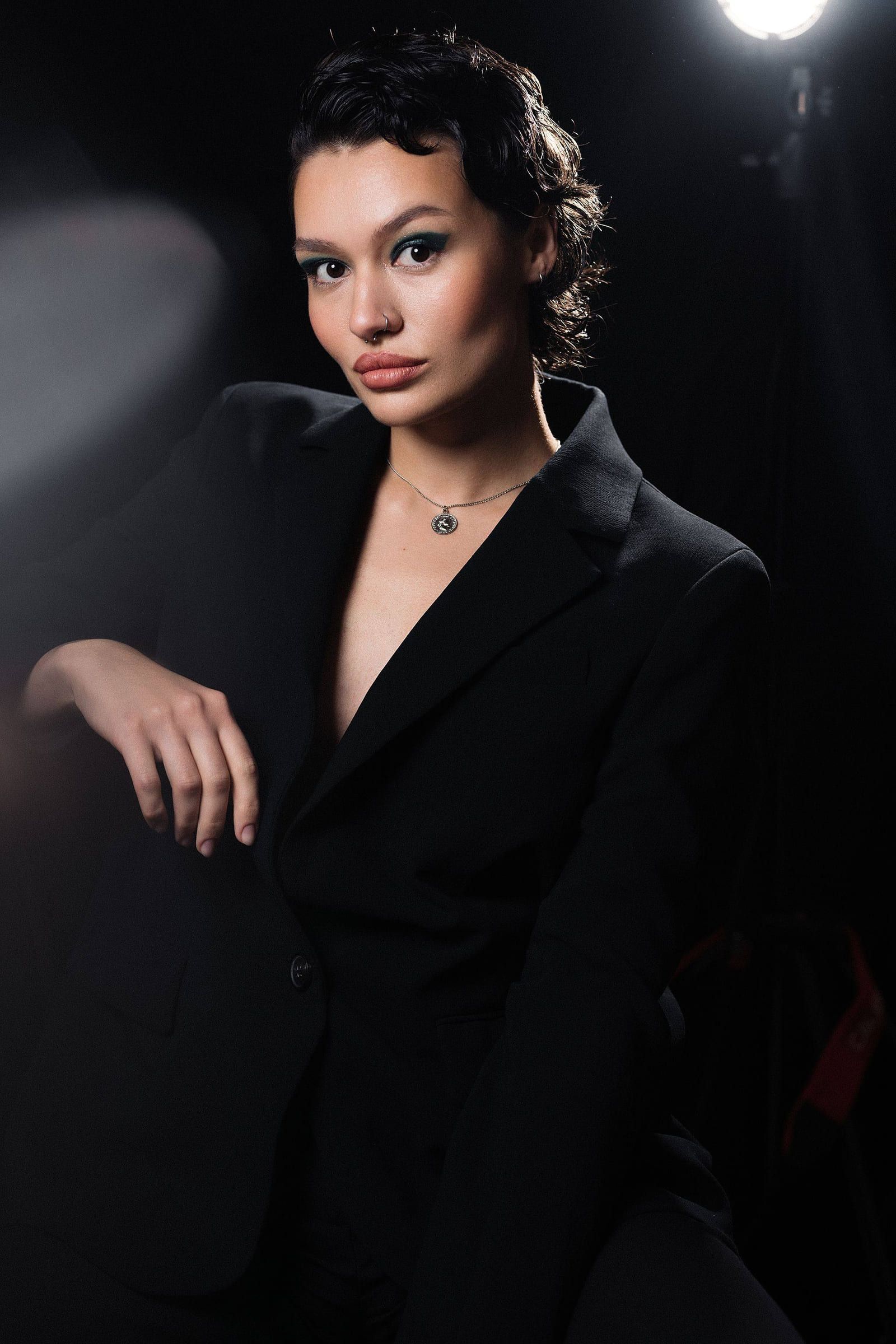 Model in a black suit against a dark studio backdrop