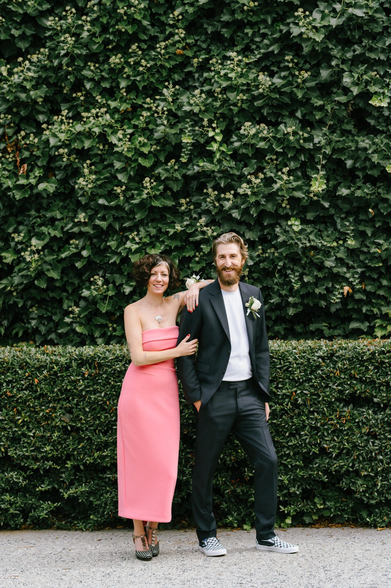 Candid wedding photography, couple laughing in front of an ivy-covered wall