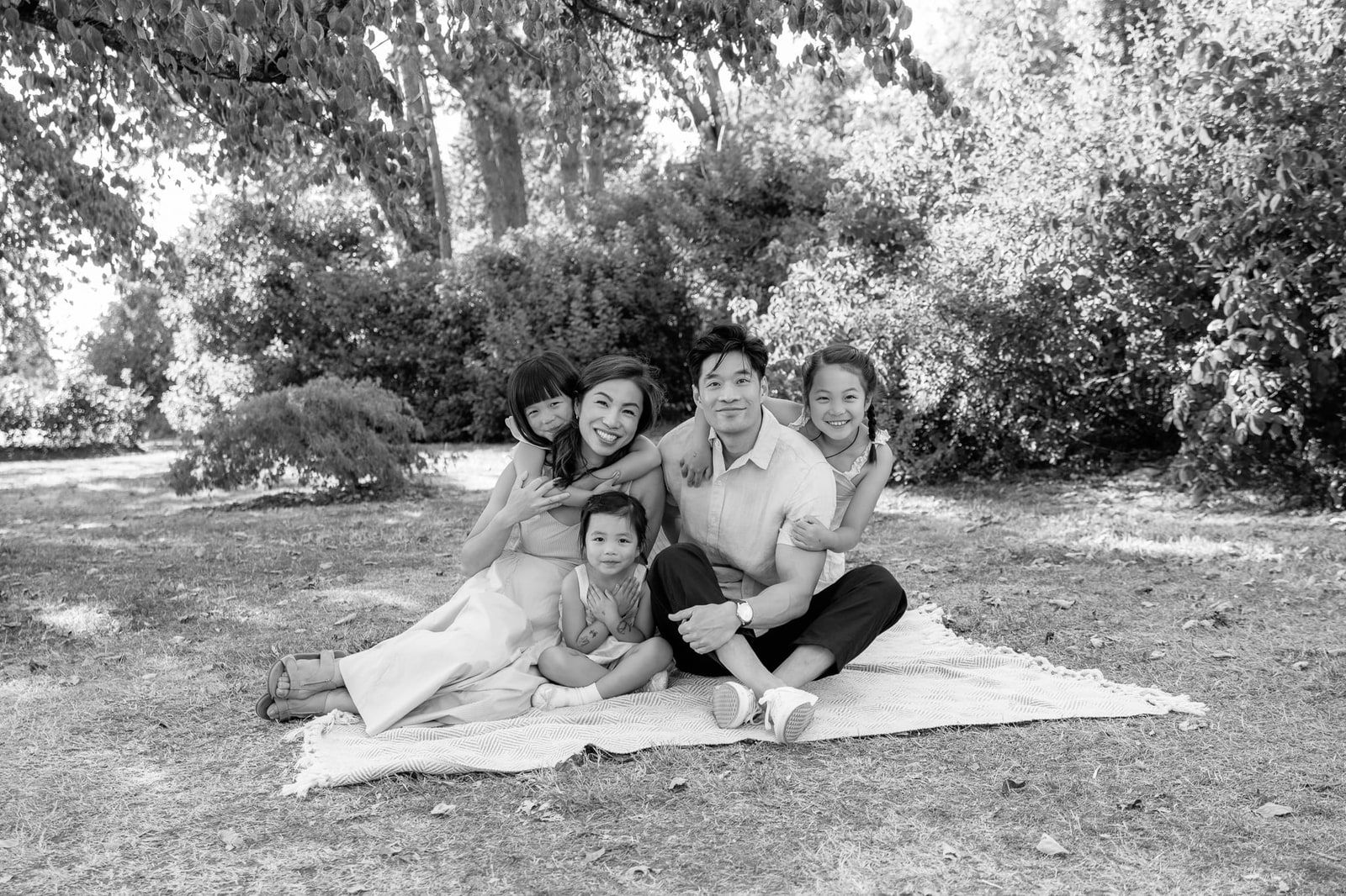 Family photography in Langley, BC, family sitting on a blanket under the trees, in black and white