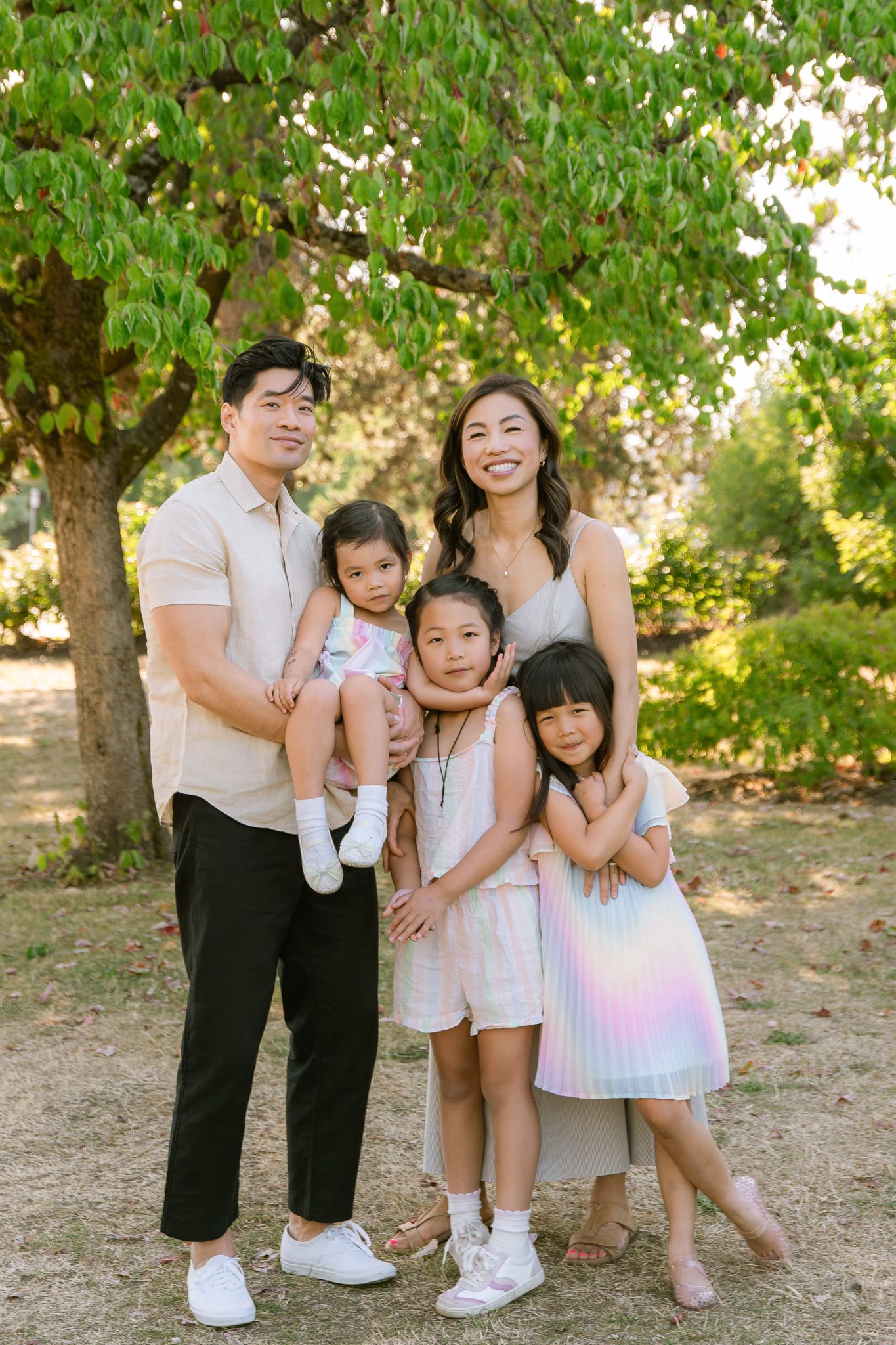 Family summer photoshoot, parents with their three daughters under a tree in summer