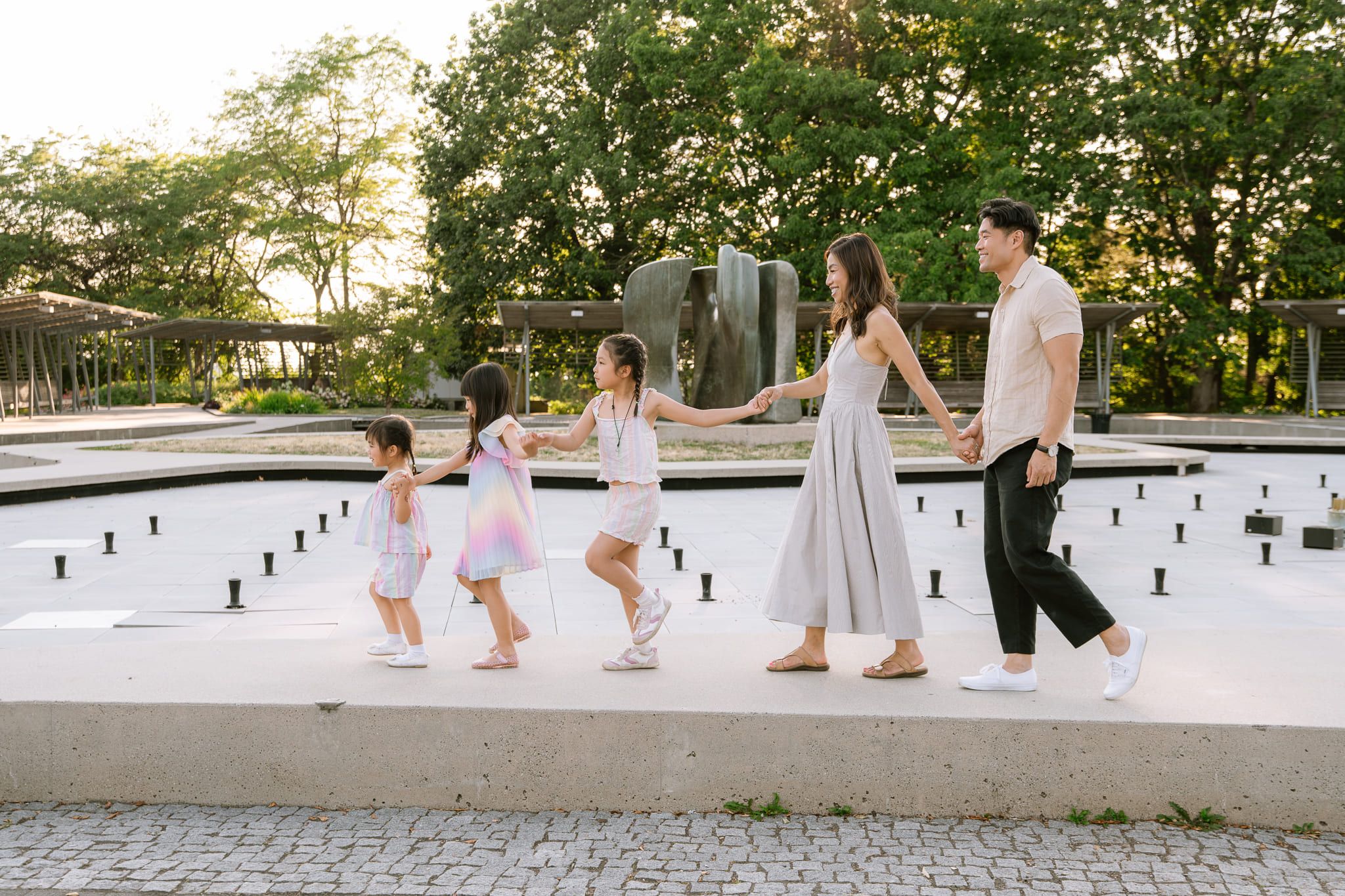 Port Moody family photographer, family walking hand in hand along the edge of a fountain