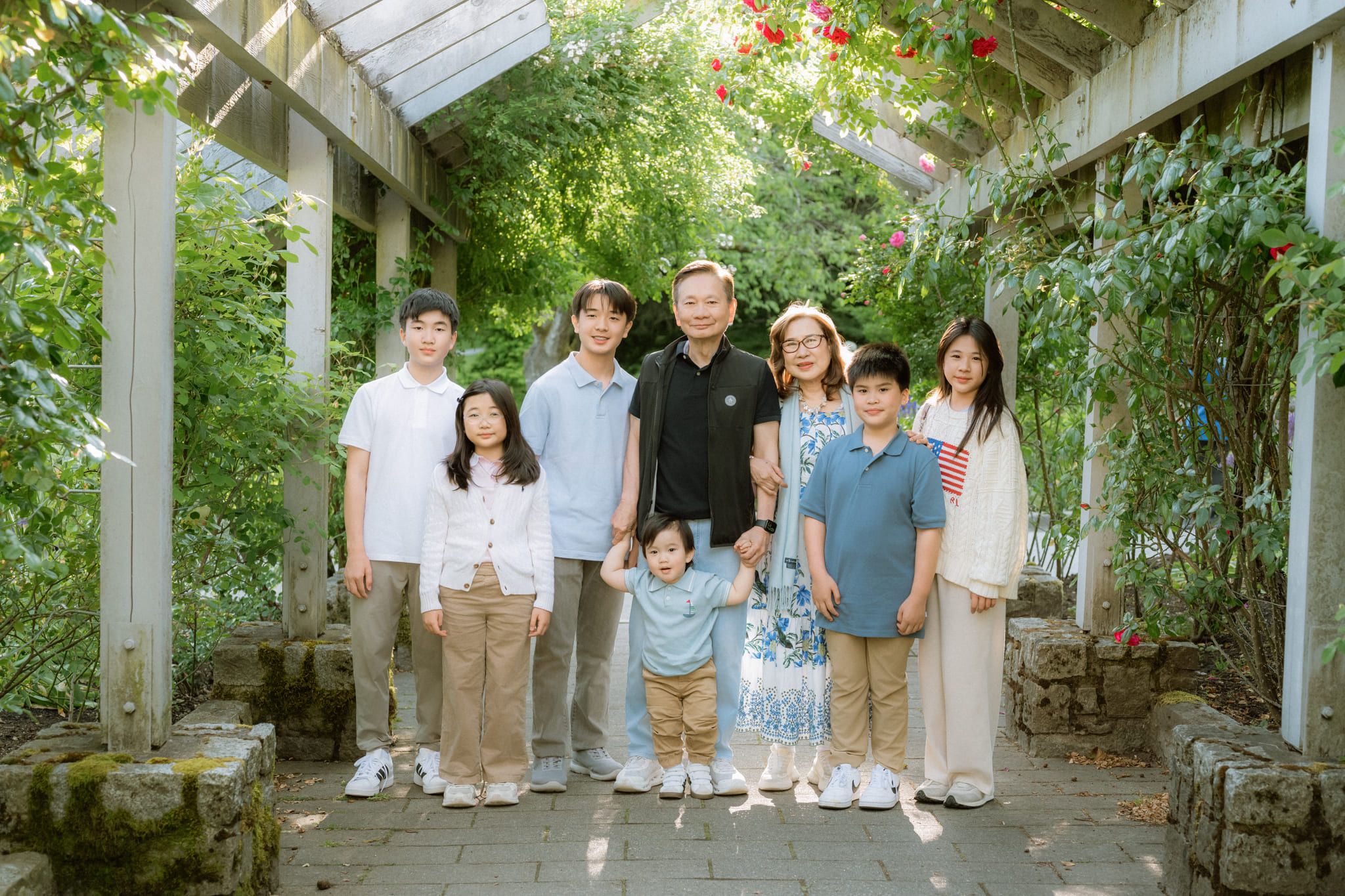 Professional family photoshoot, extended family standing under a vine-covered pergola