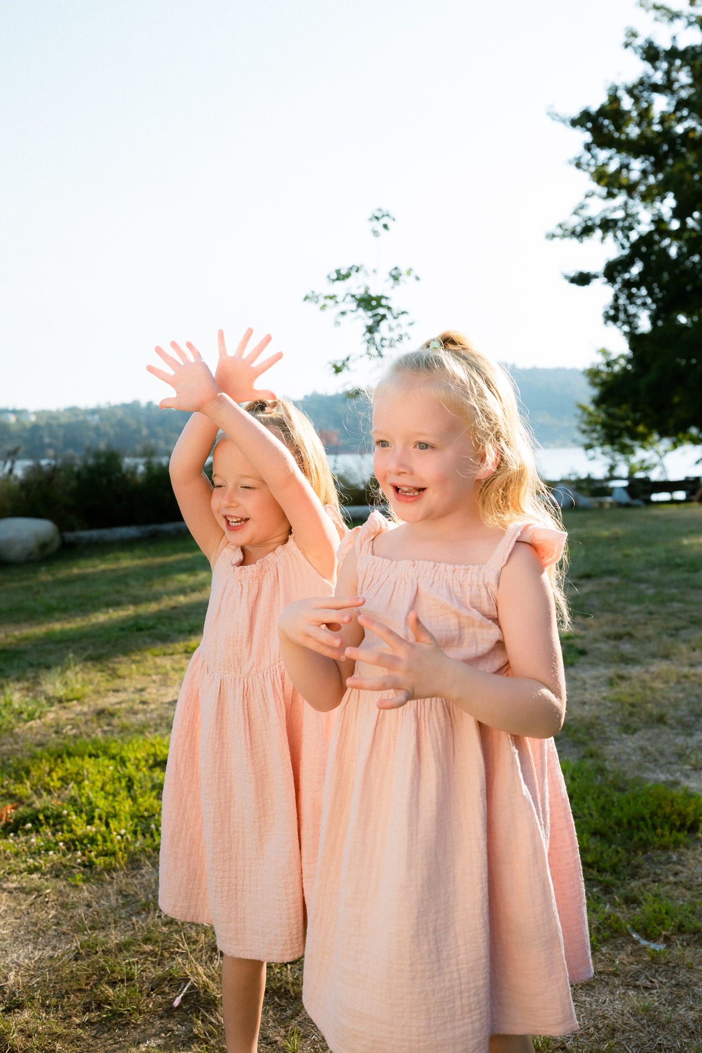 Professional family photos of two little sisters in peach dresses laughing in a field