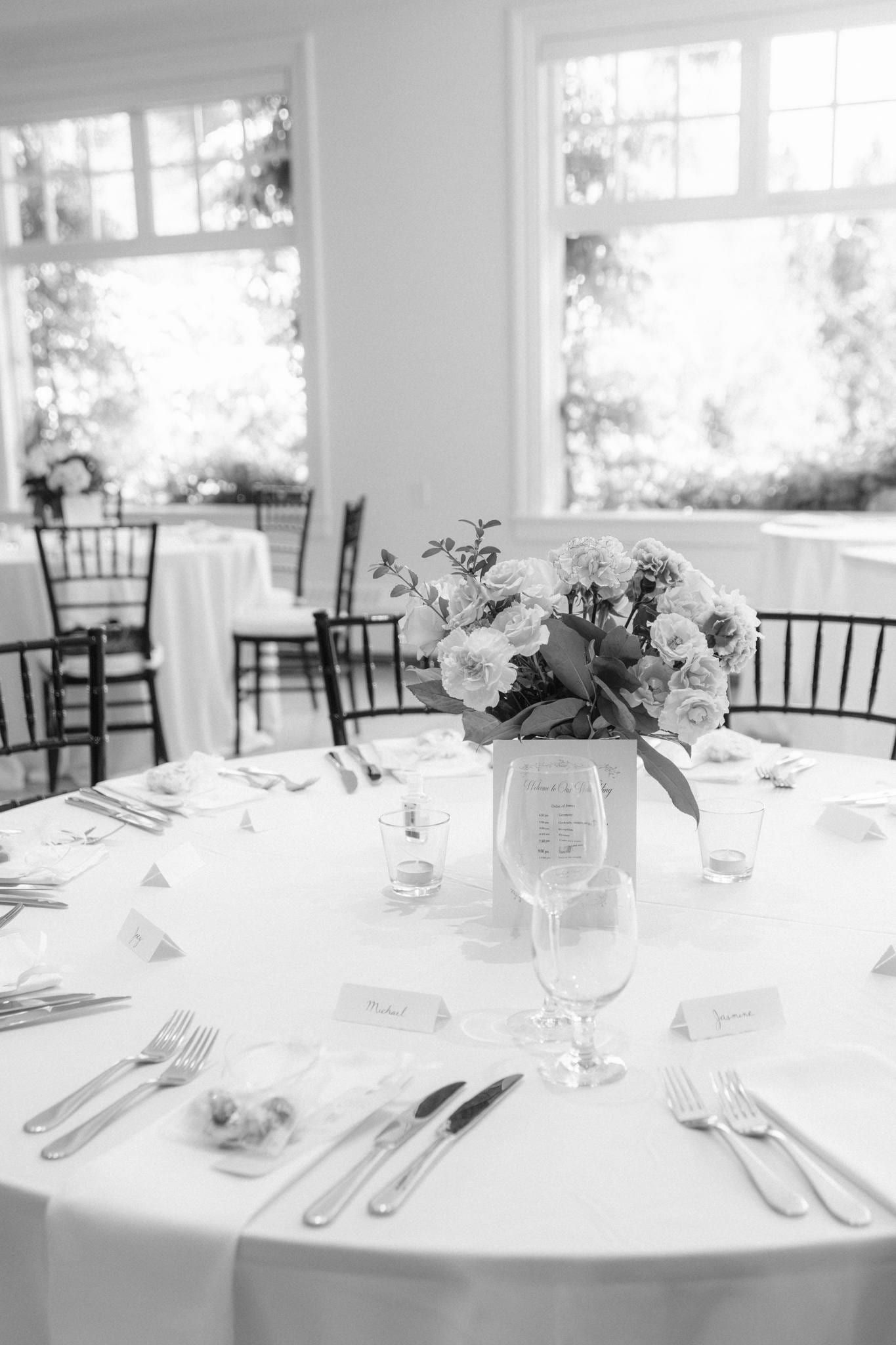 Reception table with a pink floral centrepiece by the windows