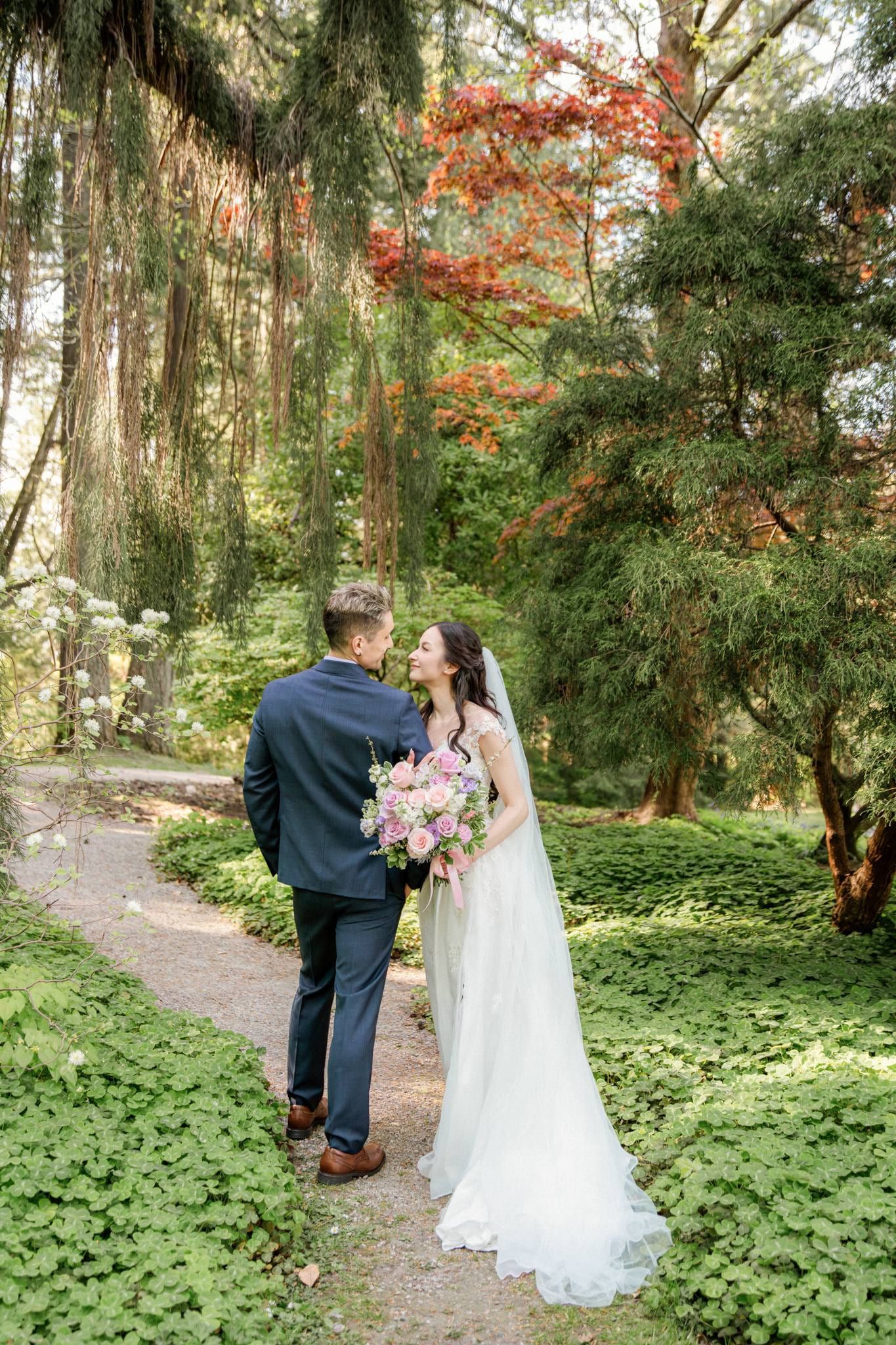 Couple standing close together on a leafy garden path