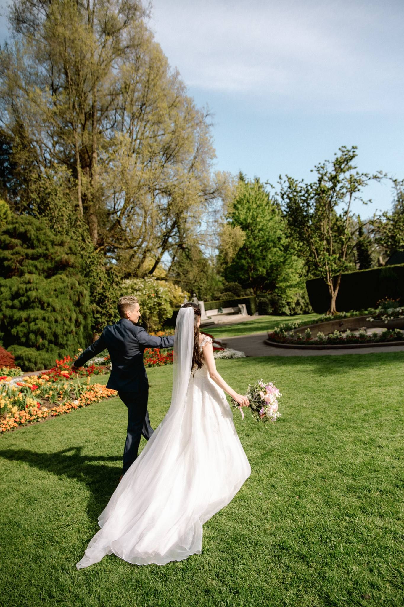 Bride and groom walking across the lawn with her train trailing