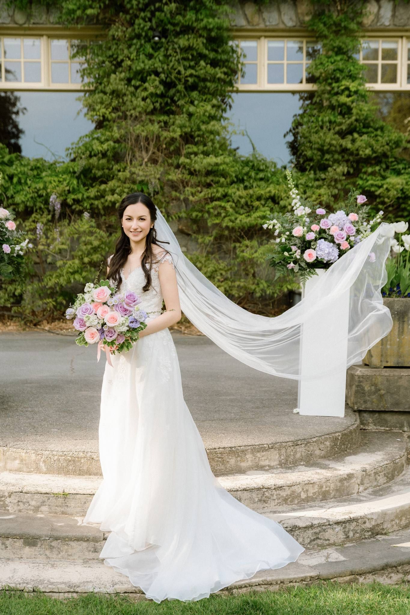 Bride holding her long veil out on the lodge steps