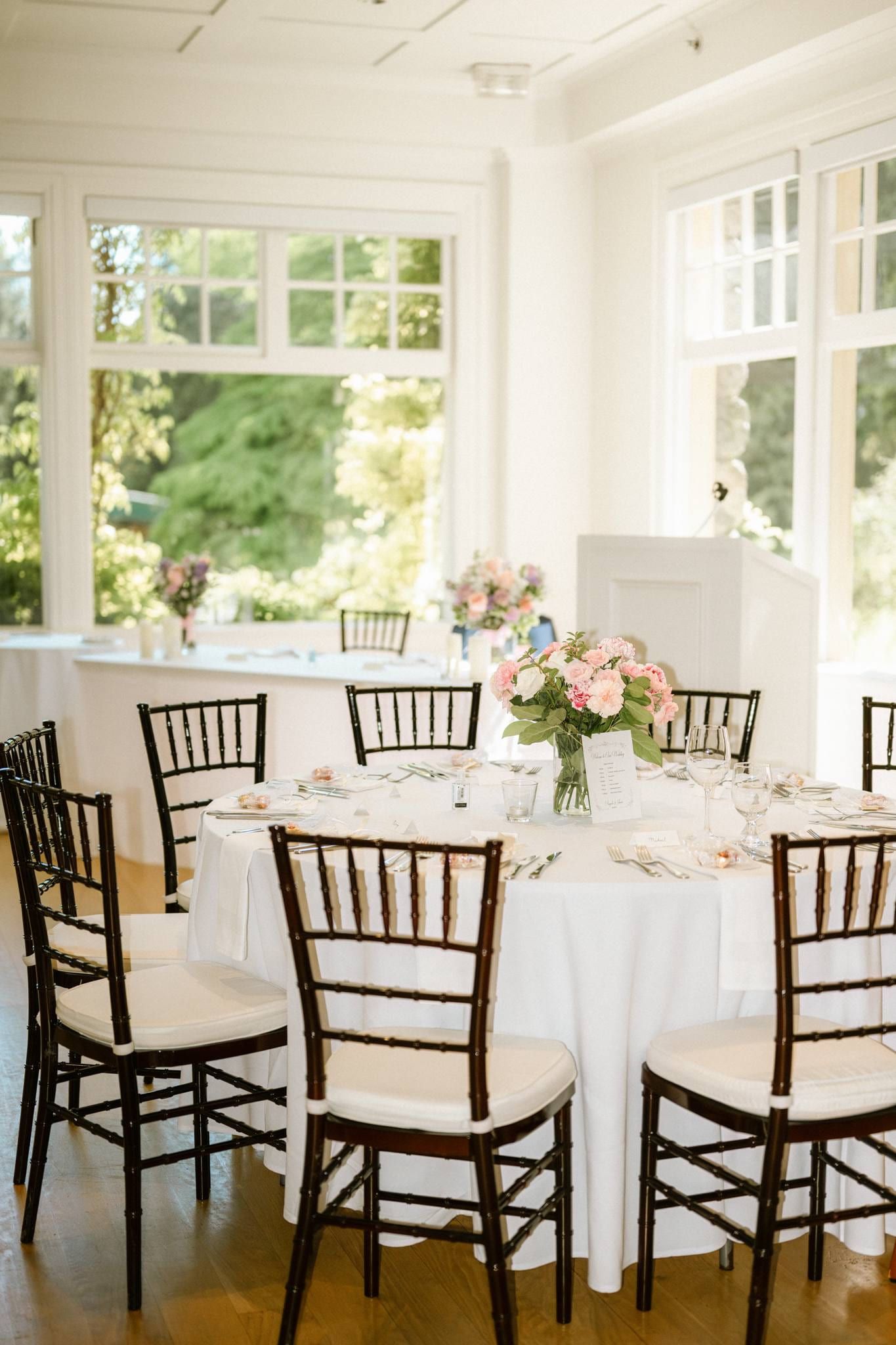 Reception tables set with white linen in the bright conservatory
